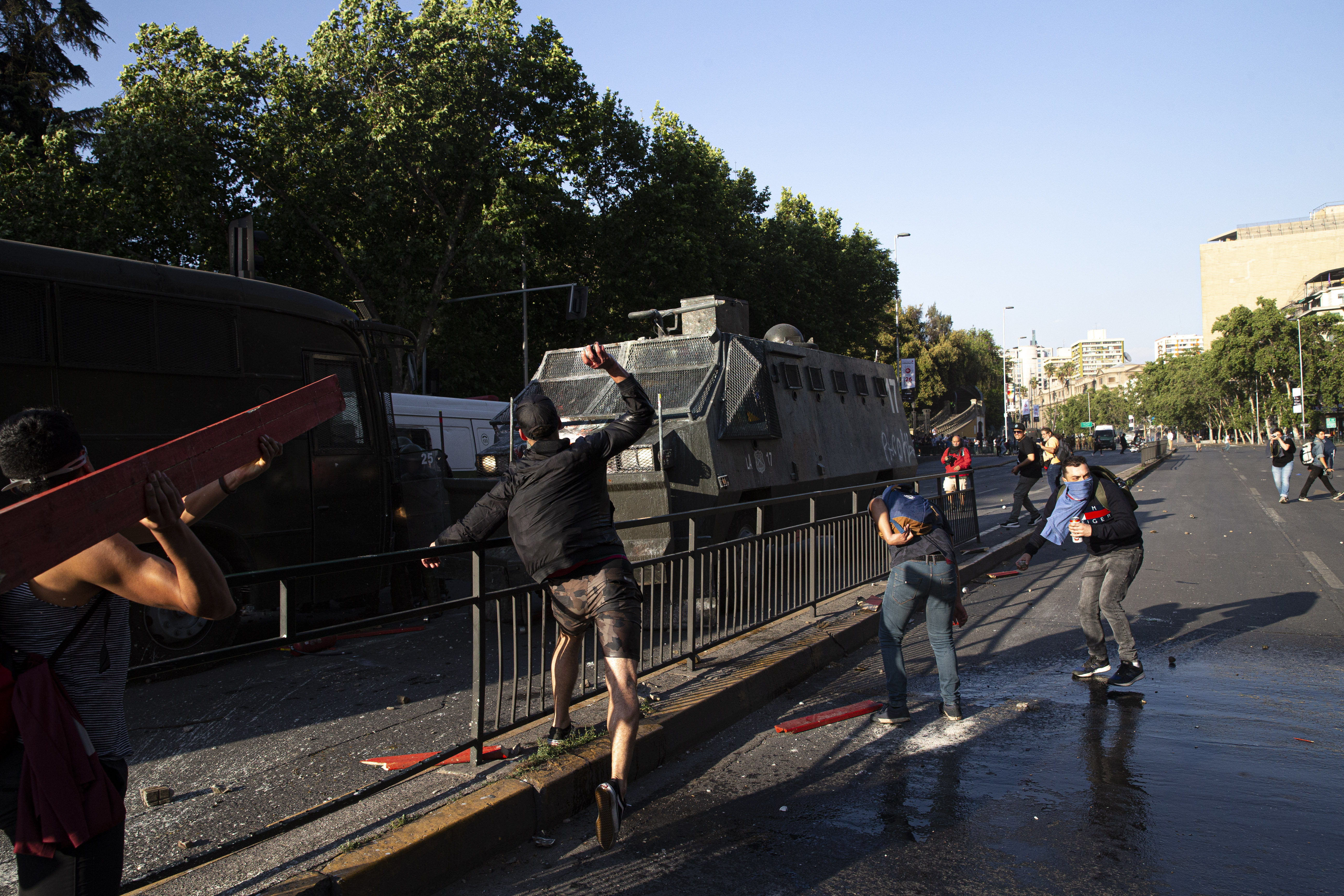A protester throws a rock at a water cannon during clashes with police in front of the Santa Lucia subway station during a protest against the rising cost of subway and bus fares, in Santiago, Friday, Oct. 18, 2019. (AP Photo/Esteban Felix)