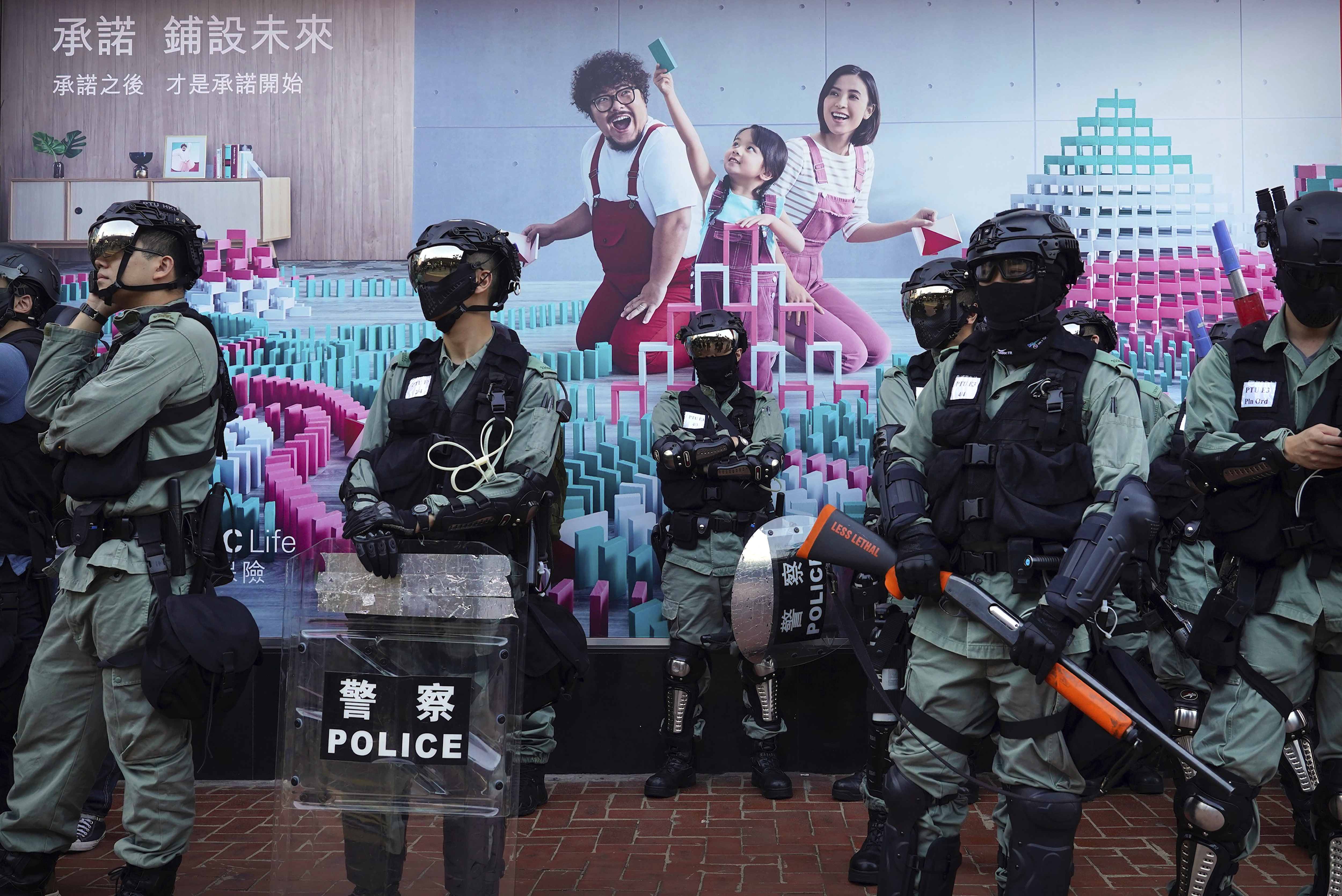 Police officers in riot gear gather in front of a billboard during an anti-government protest in Hong Kong, Saturday, Nov. 2, 2019. Defying a police ban, thousands of black-clad masked protesters are streaming into Hong Kong's central shopping district for another rally demanding autonomy in the Chinese territory as Beijing indicated it could tighten its grip. (AP Photo/Vincent Yu)