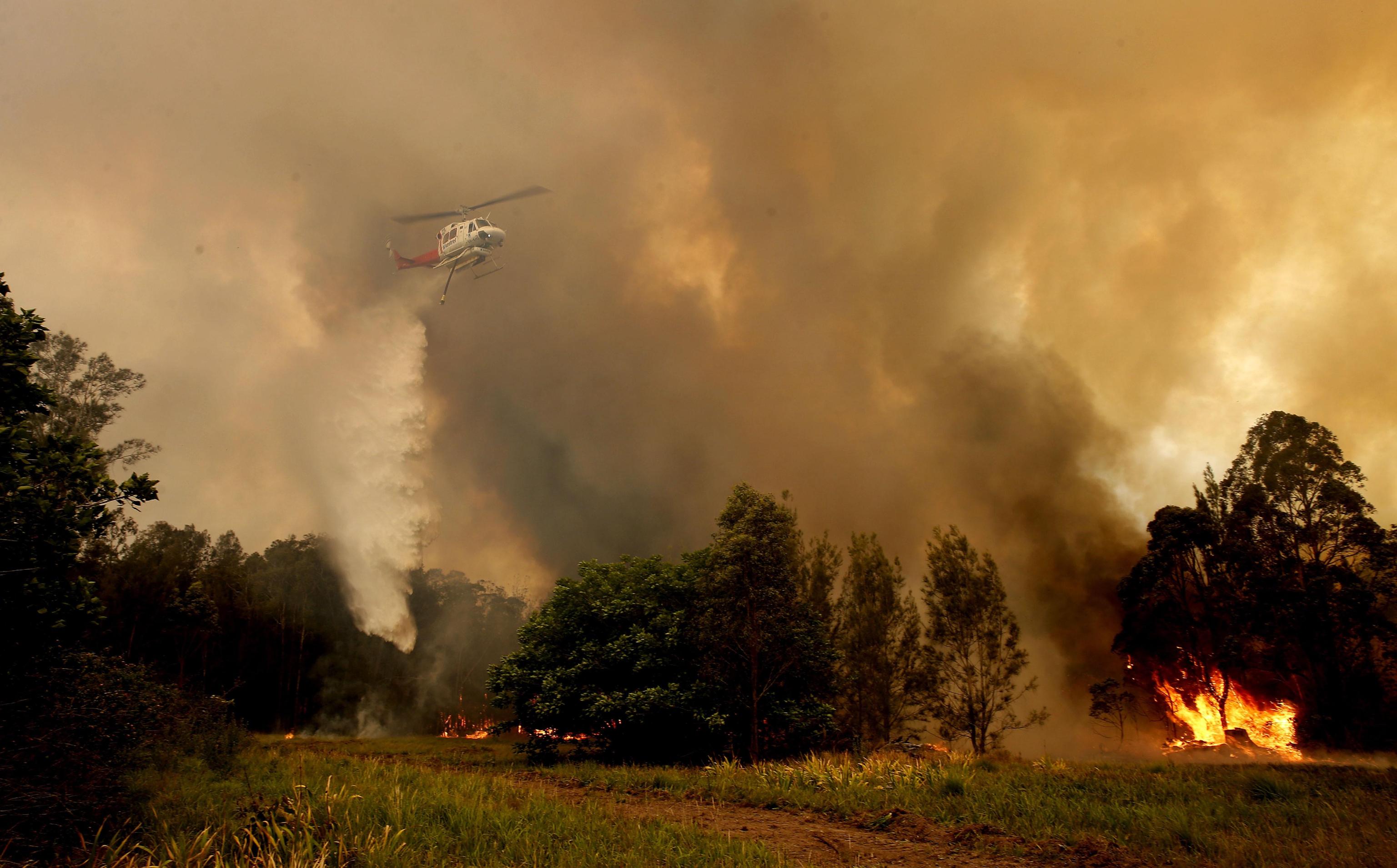 epa07982442 A fire bombing helitanker works to contain a bushfire along Old Bar road in Old Bar, New South Wales, Australia, 09 November 2019. Two people have been killed and seven others are msising due to bushfires in New South Wales, which have also destroyed at least 100 homes.  EPA/DARREN PATEMAN AUSTRALIA AND NEW ZEALAND OUT