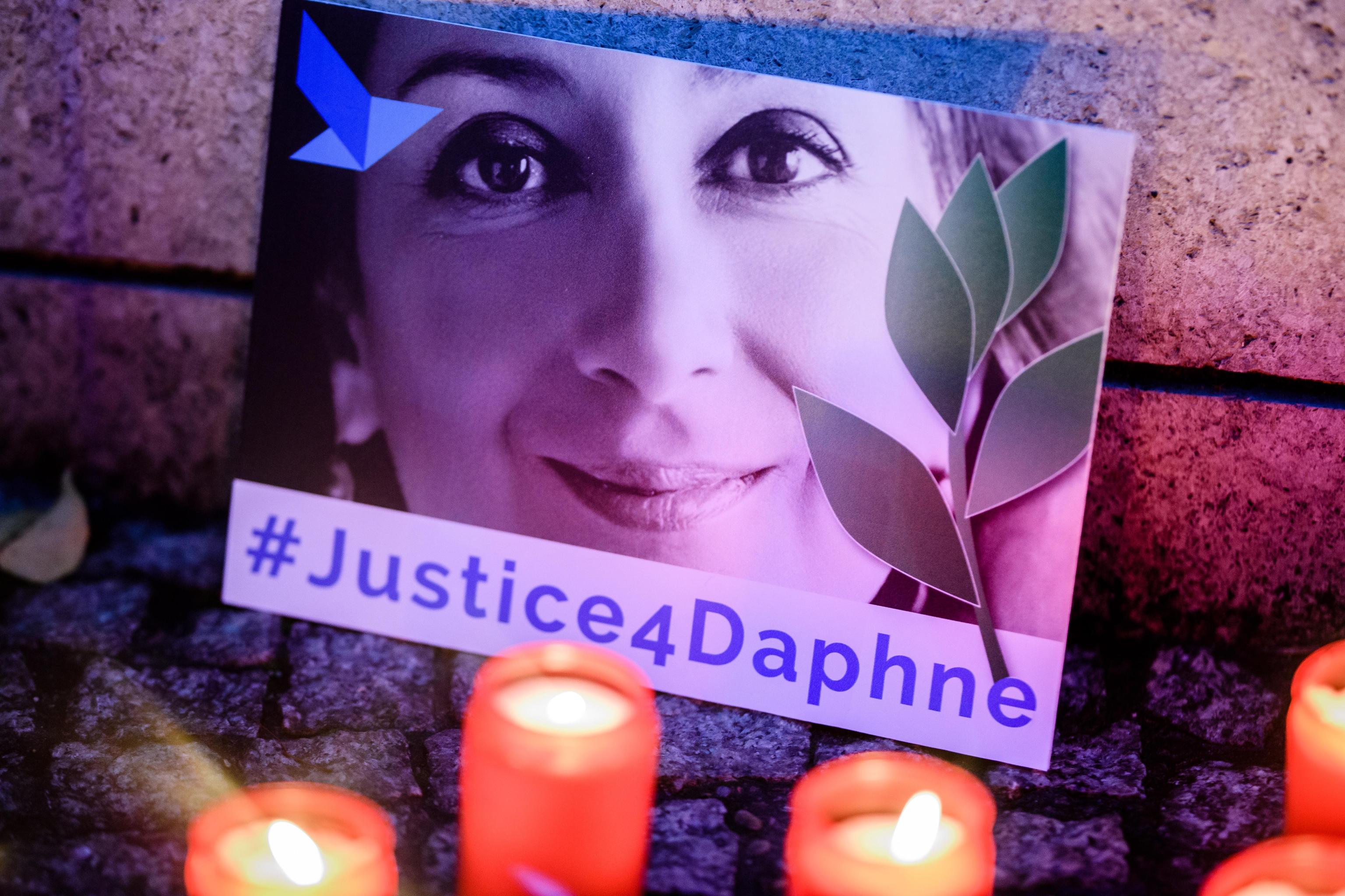epa07925848 'Justice four Daphne' is written on a cardboard showing a photo of Daphne Caruana Galizia, during a picket in front of the Maltese embassy for murdered journalist Daphne Caruana Galizia in Berlin, Germany, 16 October 2019. Reporters Without Borders organized a picket for murdered journalist Daphne Caruana Galizia, who was killed on 16 October 2017 in Malta, while investigating the Panama Papers case.  EPA/CLEMENS BILAN
