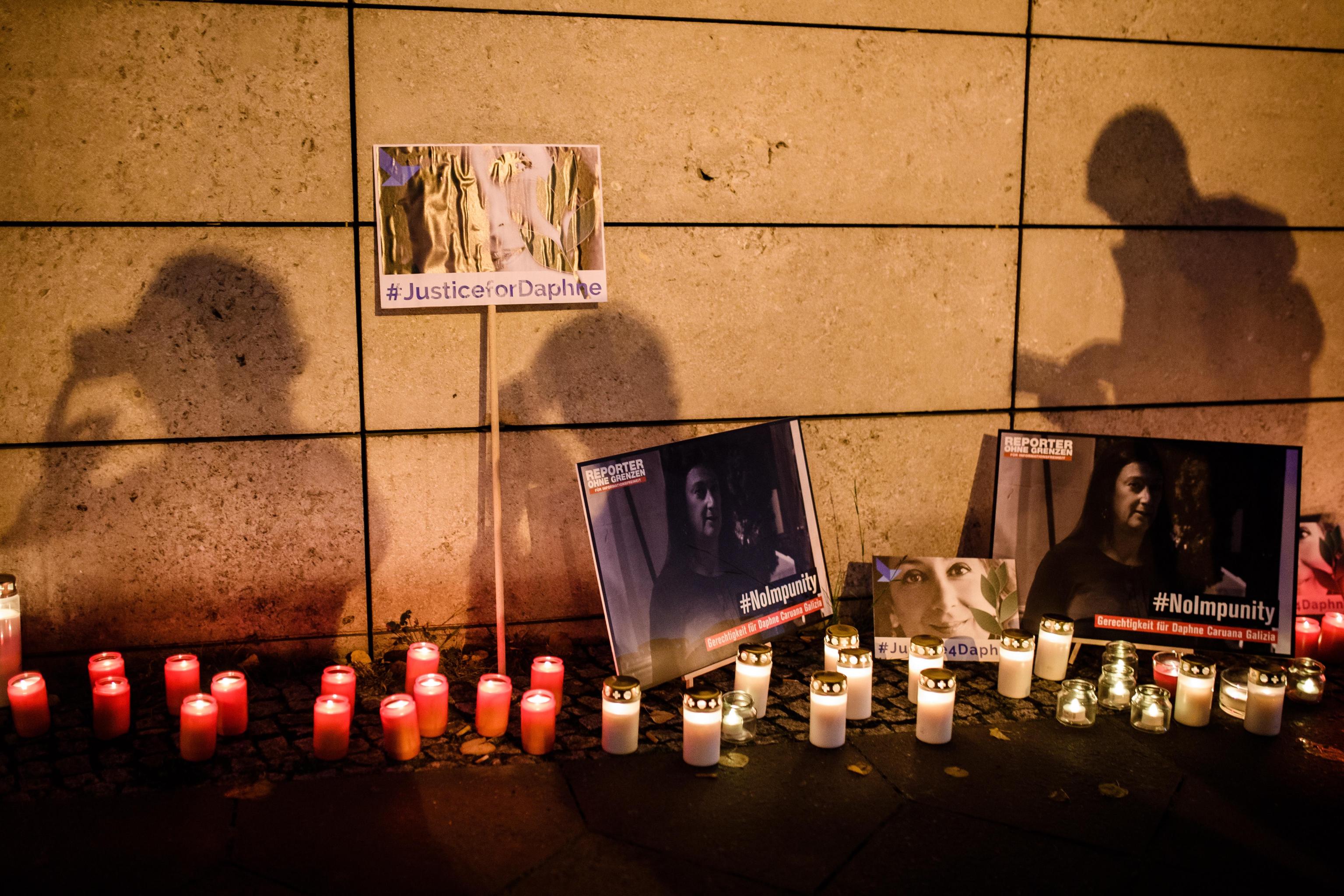 epa07925849 Filming participants cast shadows onto candles and and cardboards with photos during a picket in front of the Maltese embassy for murdered journalist Daphne Caruana Galizia in Berlin, Germany, 16 October 2019. Reporters Without Borders organized a picket for murdered journalist Daphne Caruana Galizia, who was killed on 16 October 2017 in Malta, while investigating the Panama Papers case.  EPA/CLEMENS BILAN