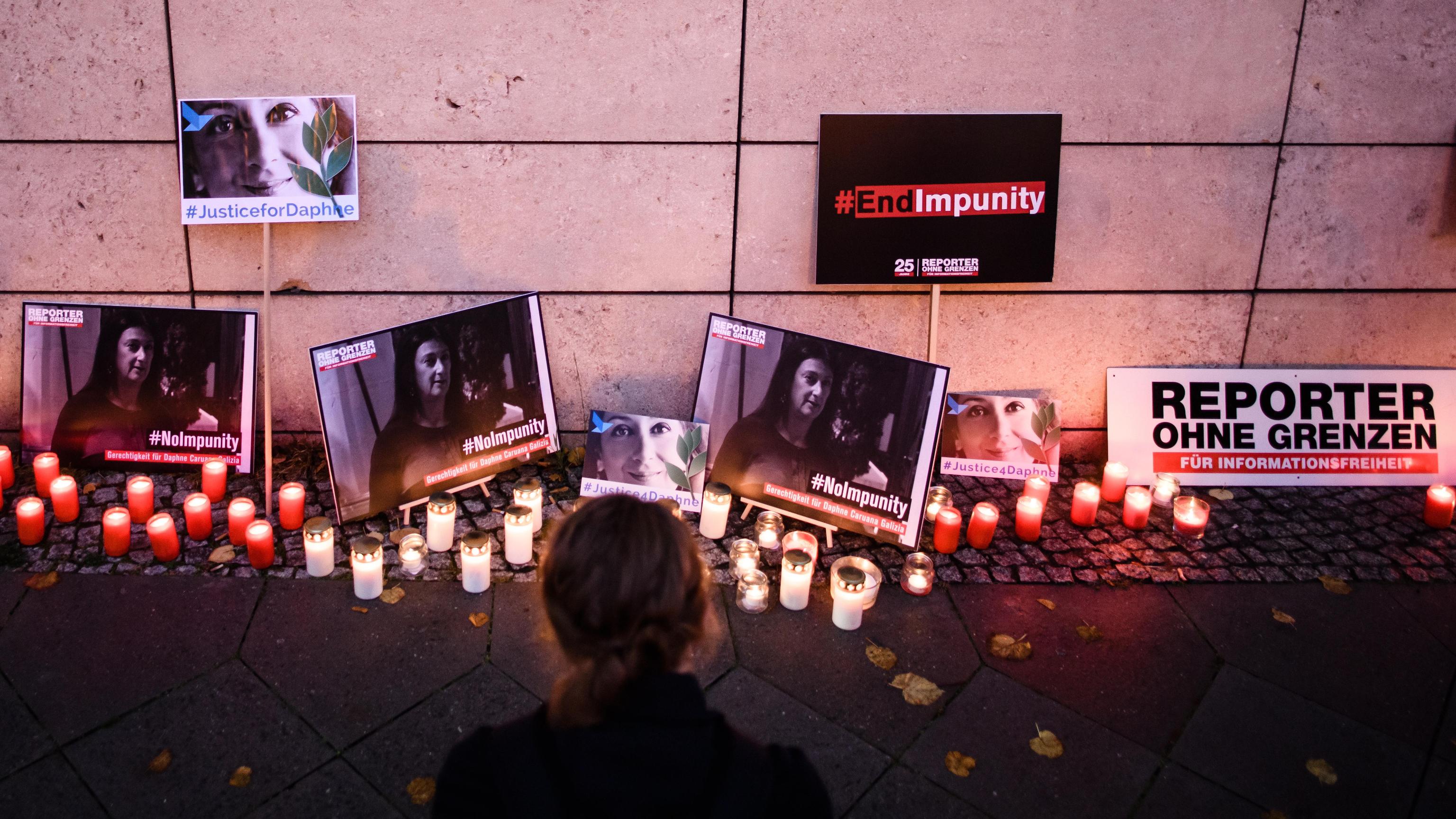 epa07925850 A woman kneels in front of candles and pictures during a picket in front of the Maltese embassy for murdered journalist Daphne Caruana Galizia in Berlin, Germany, 16 October 2019. Reporters Without Borders organized a picket for murdered journalist Daphne Caruana Galizia, who was killed on 16 October 2017 in Malta, while investigating the Panama Papers case.  EPA/CLEMENS BILAN