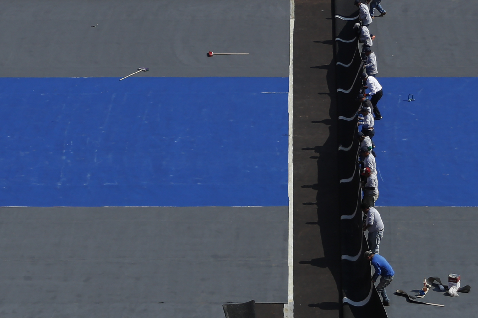 Workers lay down the court surface as they convert the Plaza de Toros Mexico bullring to host an upcoming exhibition tennis match between Swiss great Roger Federer and German rival Alexander Zverev, in Mexico City, Thursday, Nov. 21, 2019. Work began on the ring last Sunday to flatten the surface and leave it free of lumps. (AP Photo/Rebecca Blackwell)