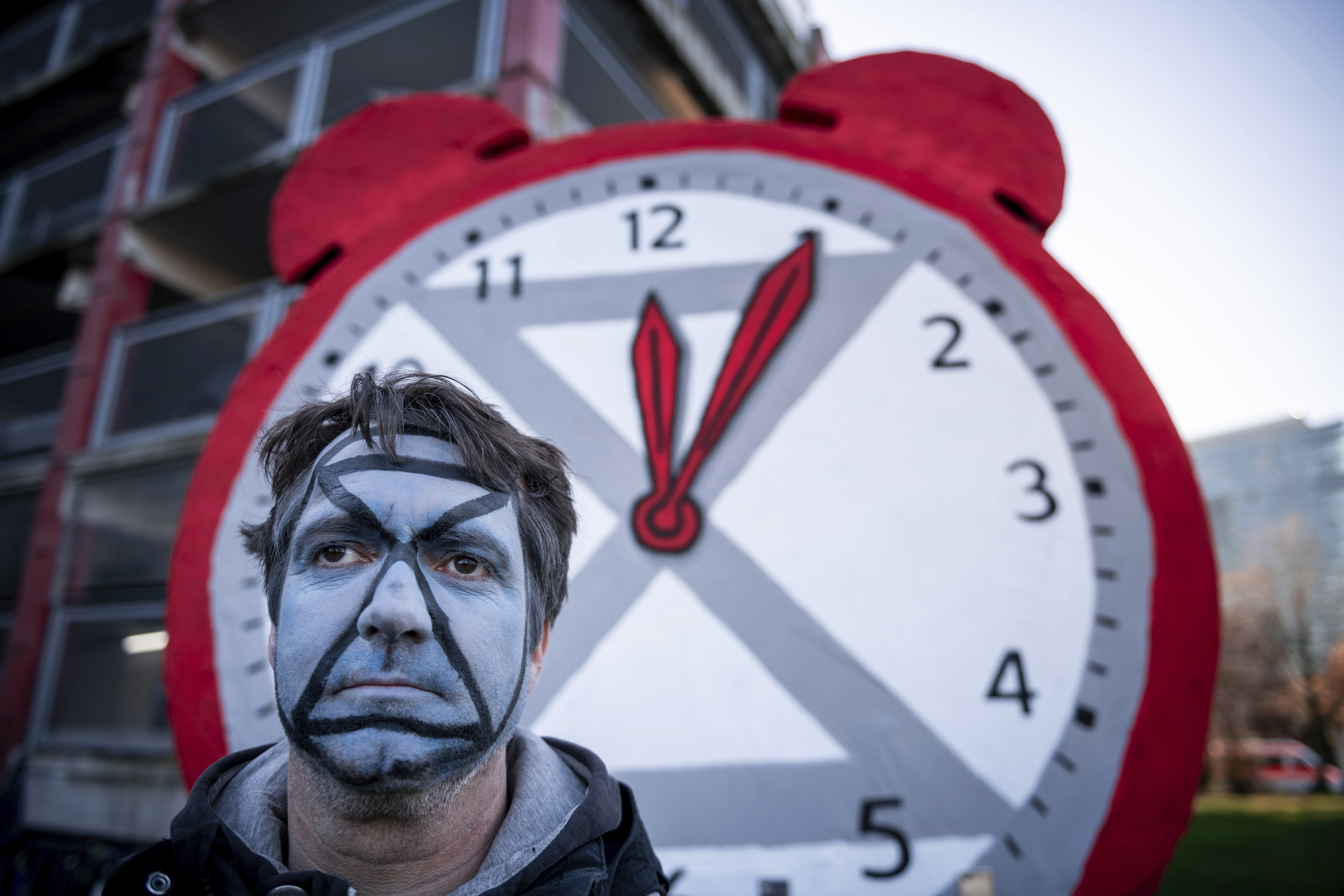 29 November 2019, North Rhine-Westphalia, Duesseldorf: A demonstrator stands in front of a clock with its hands set at five past twelve. The Fridays for Future movement demonstrates against the German government's climate package in front of the state parliament in D'sseldorf. From 2 to 13 December 2019, the 25th UN Climate Change Conference will take place in Madrid, where it will deal with the climate protection commitments of states, international trade in CO2 pollution rights and the financing of climate damage caused by droughts and storms. Photo by: Fabian Strauch/picture-alliance/dpa/AP Images