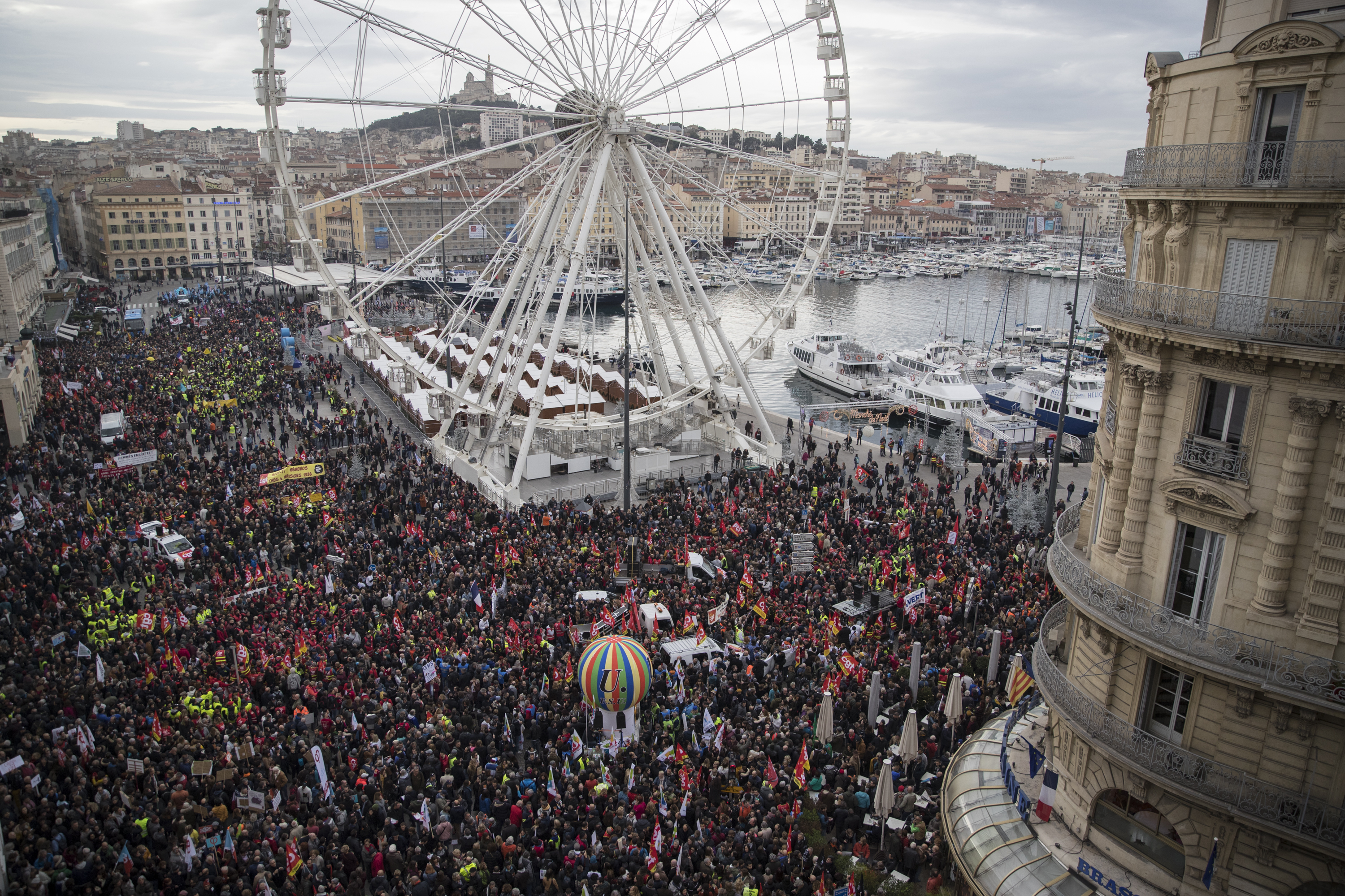 Protesters march during a mass stirke in the Old Port of Marseille, southern France, Wednesday, Dec. 5, 2019. Workers across the public sector fear President Emmanuel Macron's reform will force them to work longer and shrink their pensions. AP Photo/Daniel Cole)