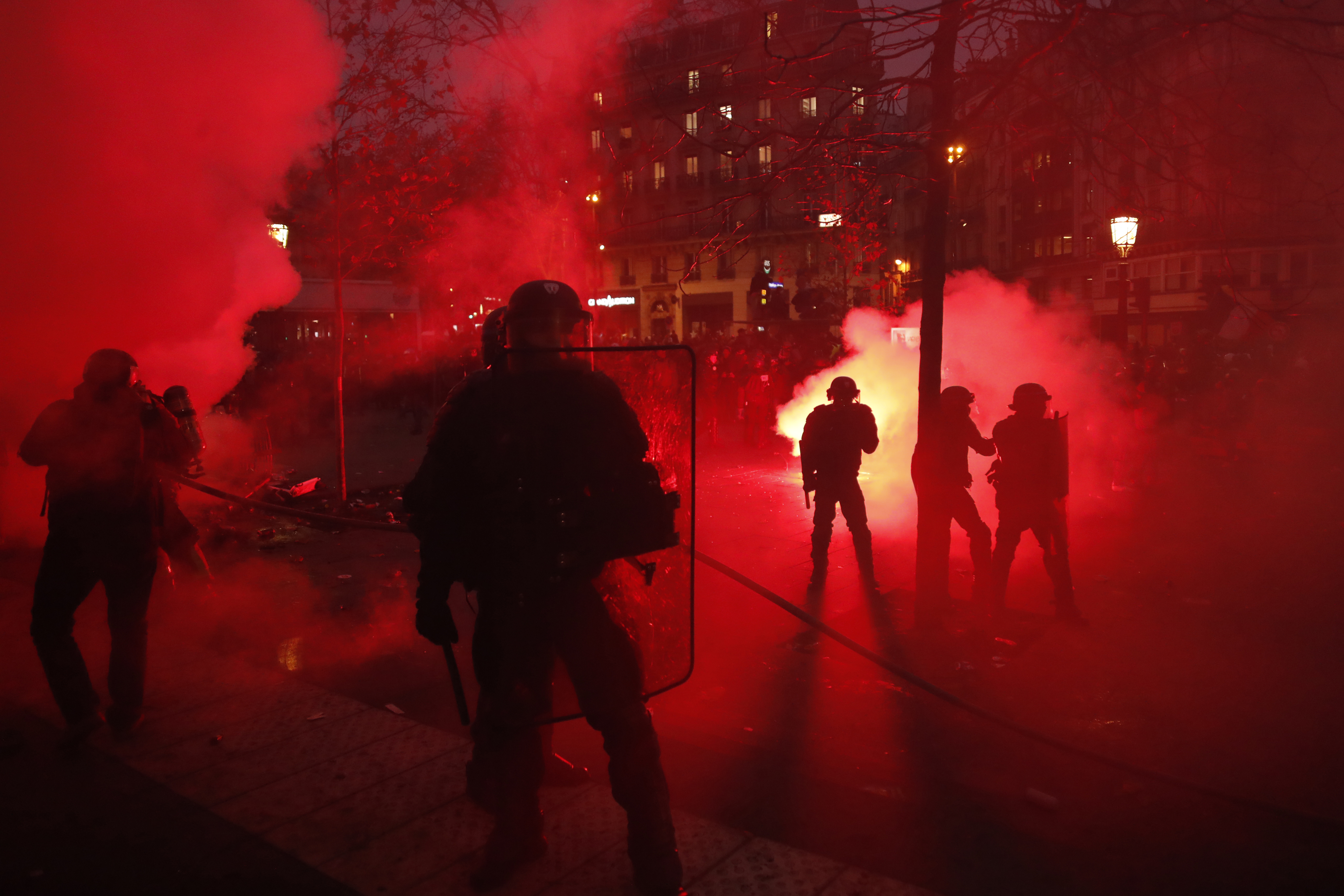 Riot police officers secure an area during a demonstration in Paris, Thursday, Dec. 5, 2019. Small groups of protesters are smashing store windows, setting fires and hurling flares in eastern Paris amid mass strikes over the government's retirement reform. (AP Photo/Thibault Camus)