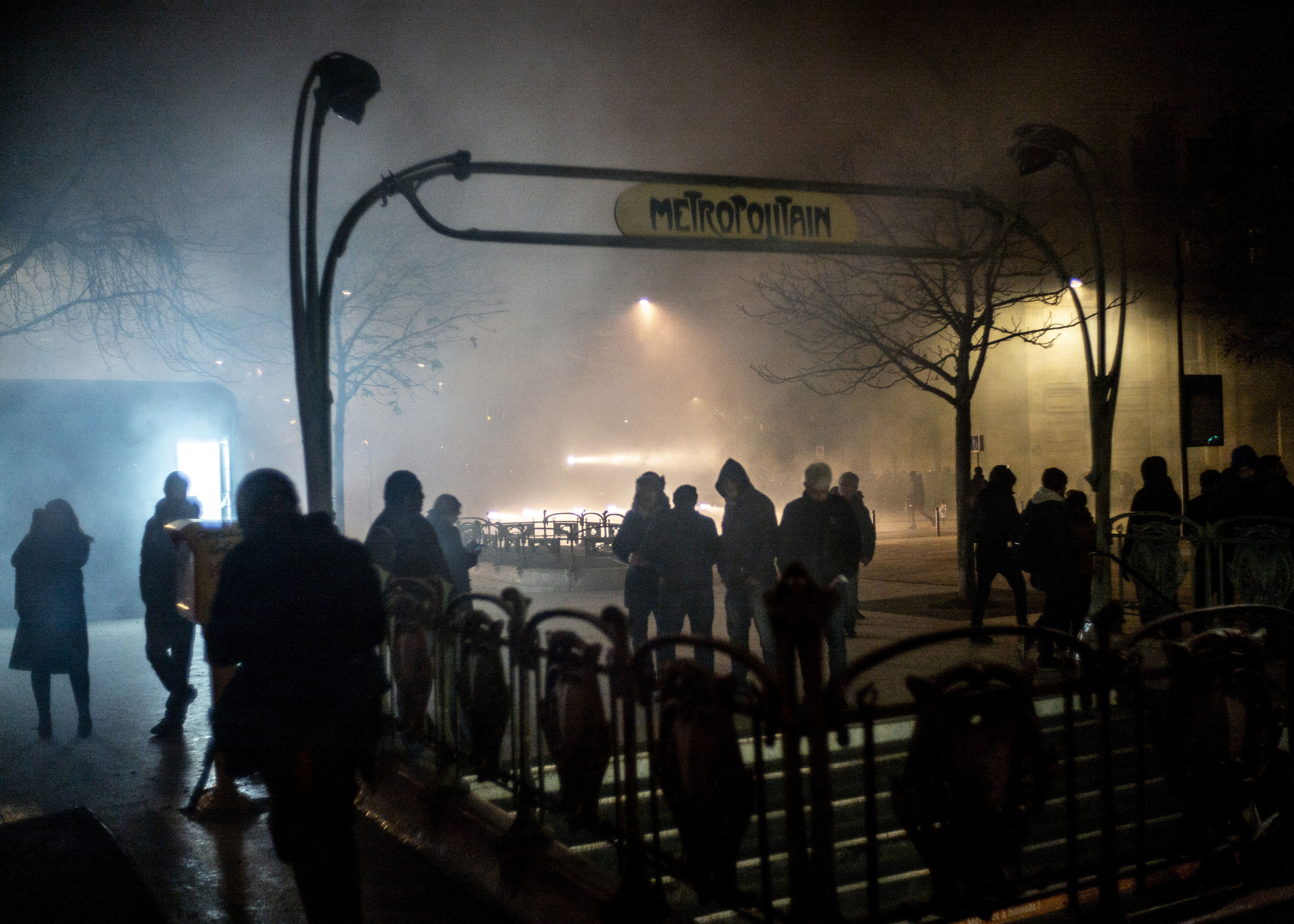 People stand next to the entrance of a metro station at the end of a demonstration in Paris, Thursday, Dec. 5, 2019. The Eiffel Tower shut down, France's high-speed trains stood still and tens of thousands of people marched through Paris and other cities Thursday, in a massive and sometimes chaotic outpouring of anger at the government's plan to overhaul the retirement system. (AP Photo/Rafael Yaghobzadeh)