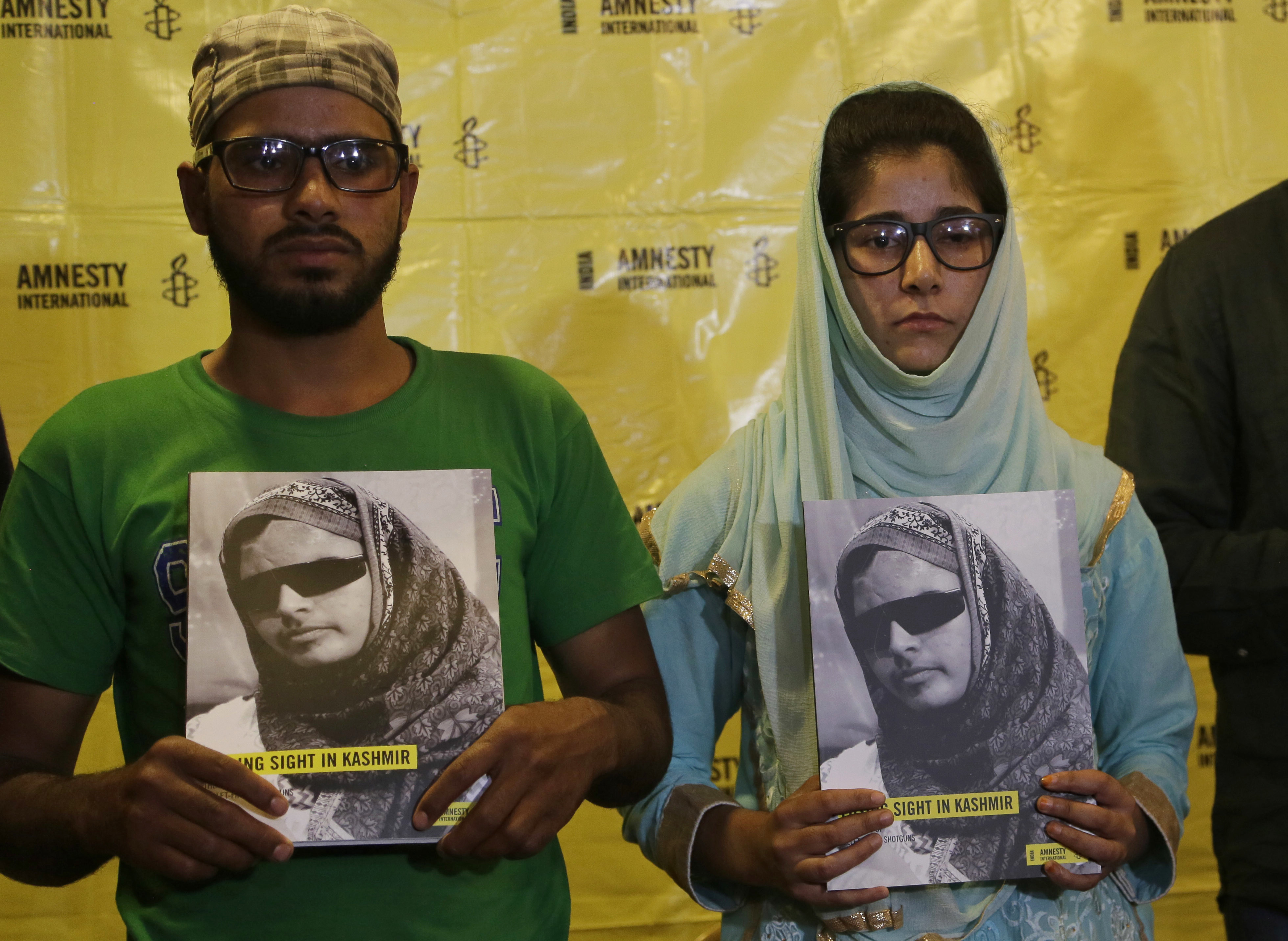 Shotgun victims victims Manzoor Ahmed, left and Shabrooza Mir, hold copies of a report by Amnesty International during its release in Srinagar, Indian controlled Kashmir, Wednesday, Sept. 13, 2017. The human rights group has called on India to immediately ban the use of shotguns by government forces in suppressing protests against Indian rule in disputed Kashmir, saying pellets fired by the weapons have blinded and killed people indiscriminately. (AP Photo/Mukhtar Khan)