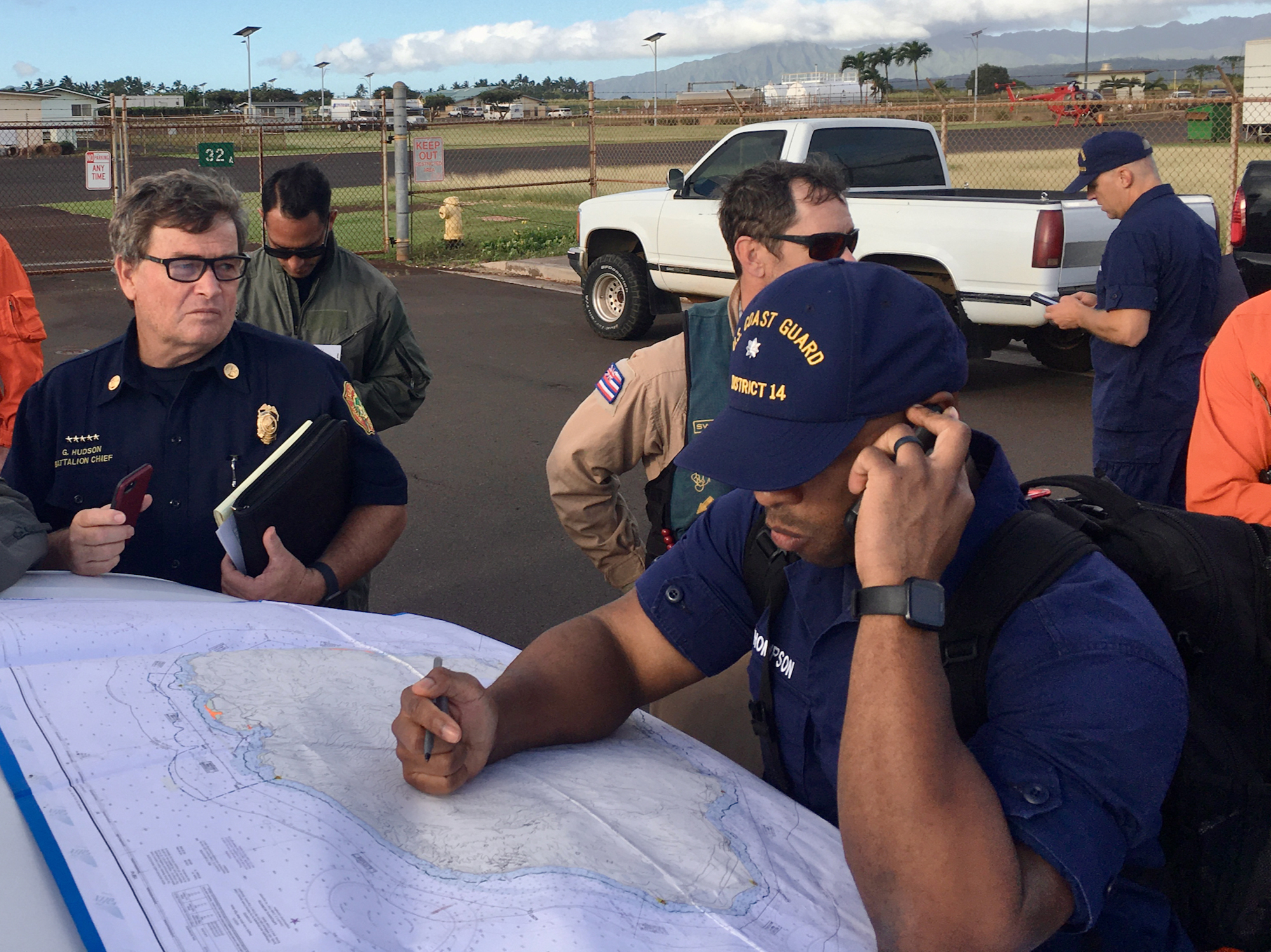 In this photo released by the U.S. Coast Guard, Coast Guard Incident Command Post responders look over a map of the Na Pali Coast State Wilderness Park on the Hawaiian island of Kauai on Friday, Dec. 27, 2019, the day after a tour helicopter disappeared with seven people aboard. Authorities say wreckage of the helicopter has been found in a mountainous area on the island. (Senior Chief Justin Shackleford/U.S. Coast Guard via AP)