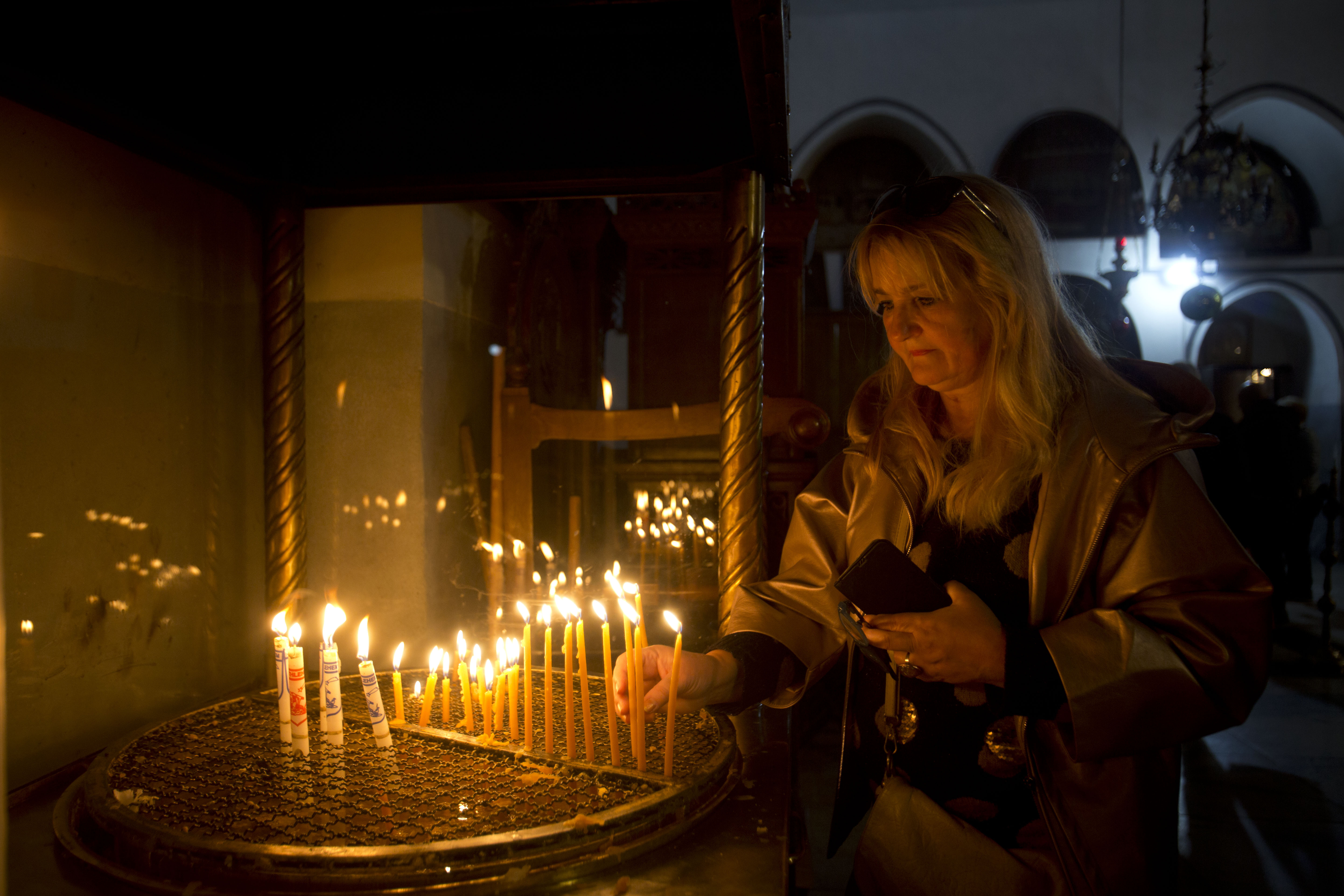 A visitor lights a candle at the Church of the Nativity built on top of the site where Christians believe Jesus Christ was born on Christmas Eve, in the West Bank City of Bethlehem, Tuesday, Dec. 24, 2019. (AP Photo/Majdi Mohammed)