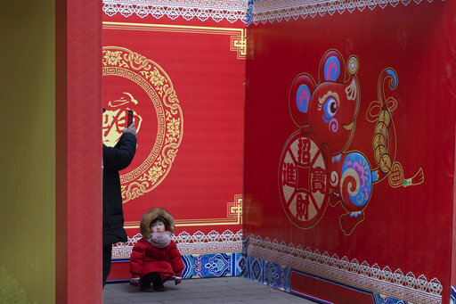 A child squats near a depiction of a rat ahead of the Chinese Lunar New Year celebrations in Beijing on Thursday, Jan. 16, 2020. The world's largest annual migration begins this week in China with millions of Chinese traveling to their hometowns to celebrate the Lunar New Year on Jan. 25 this year which marks the Year of the Rat on the Chinese zodiac. (AP Photo/Ng Han Guan)