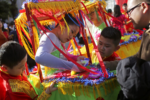 A girl fixes a flower on her costume while waiting to start in a parade opening the Chinese New Year celebrations in Lisbon, Saturday, Jan. 18, 2020. The Chinese Lunar New Year of the Rat, the first of the 12 animals of the Chinese Zodiac, officially begins on Jan. 25. (AP Photo/Armando Franca)
