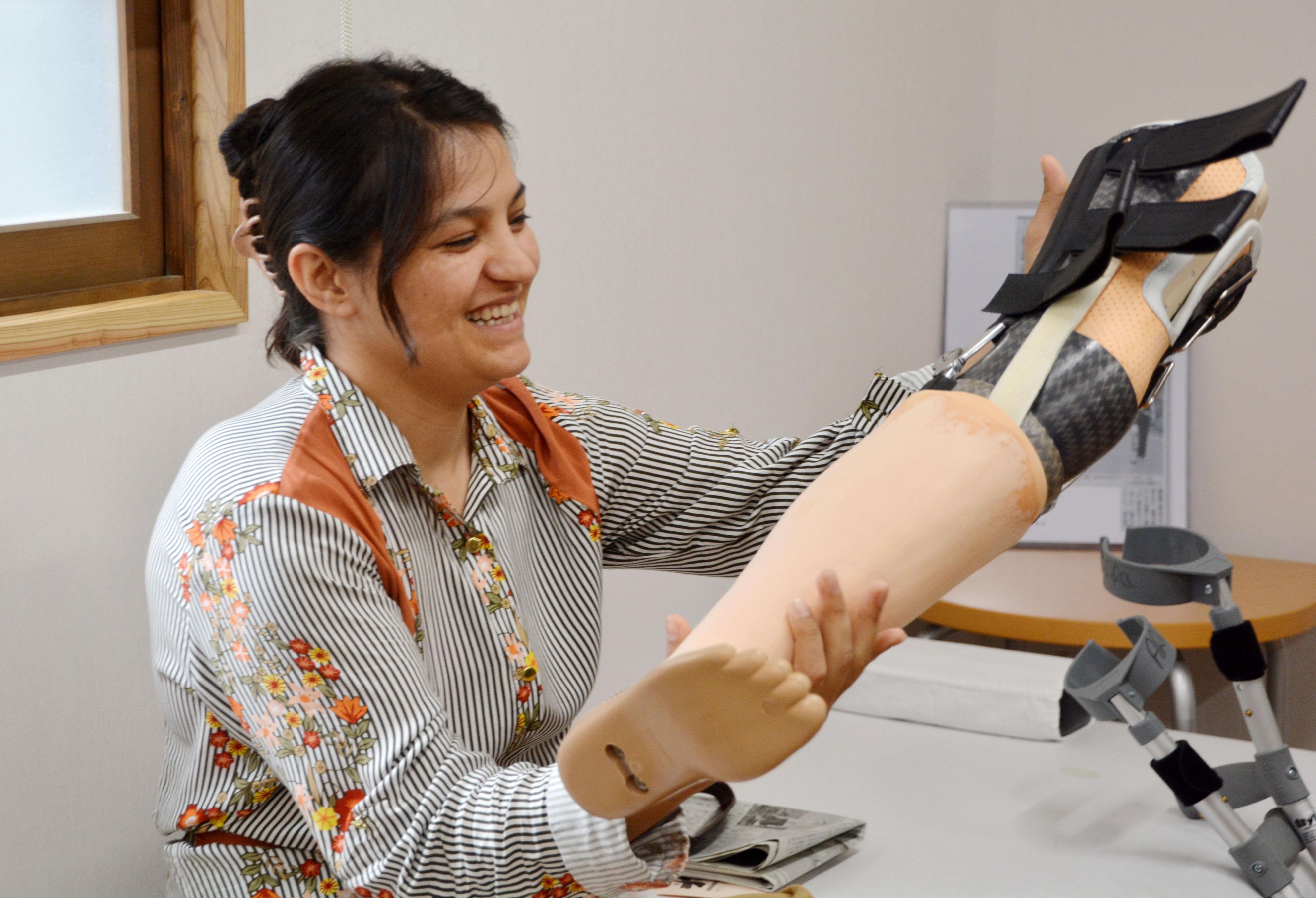 Photo taken in July 2017 in Ota, Shimane Prefecture shows Amiri Afifa, a 24-year-old Afghan woman who lost one of her legs to a landmine at age 4, smiling while holding her new artificial limb, crafted by a Japanese prosthetist in the western Japan city. (Kyodo)
==Kyodo