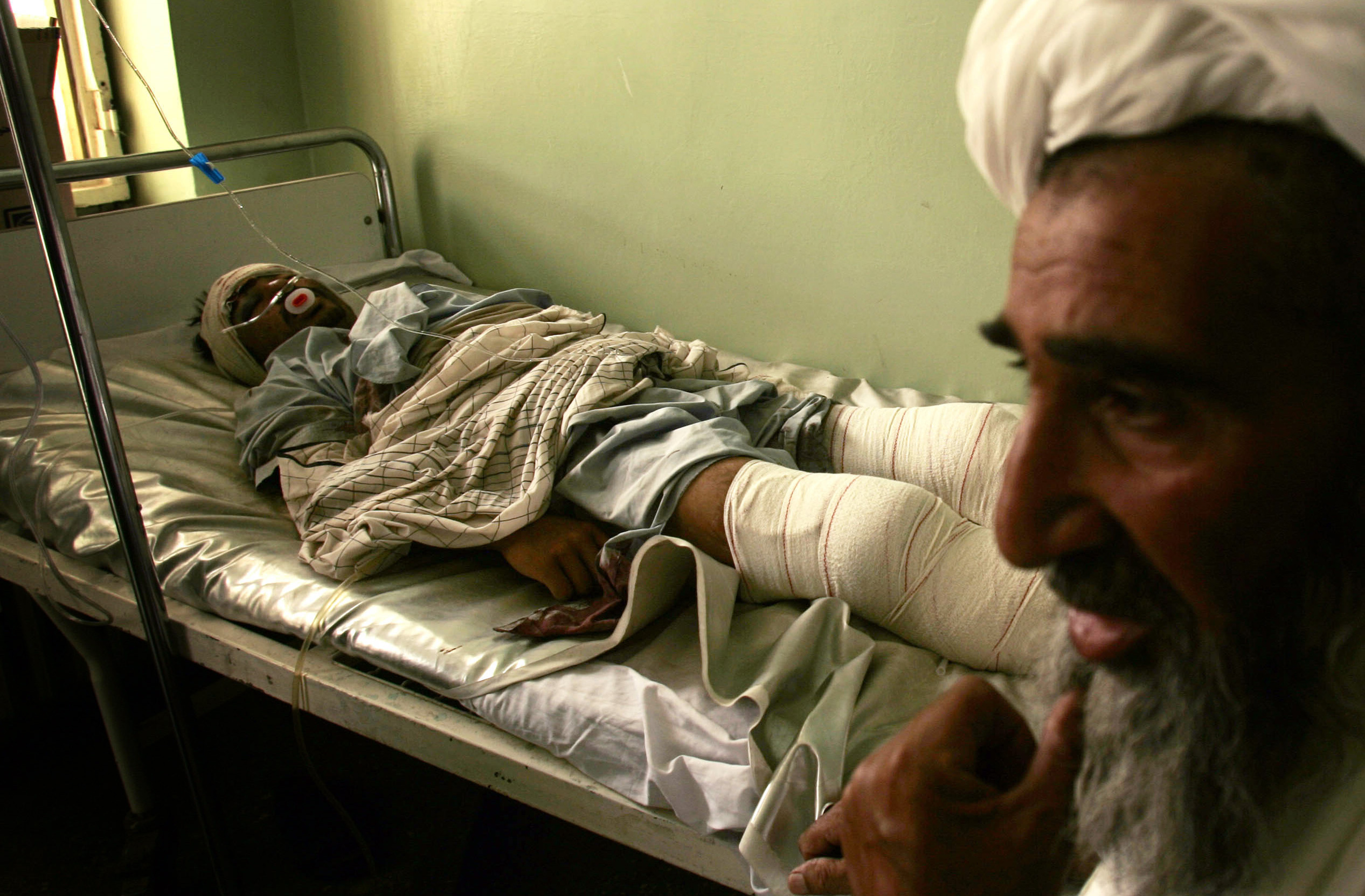 An Afghan man sits with his relative who was injured in a landmine explosion in Herat, west of Kabul, Afghanistan, Sunday, Aug. 22, 2010. Insurgents in Kandahar province, one of Afghanistan's most violent, killed the head of a private security company on Saturday, while one civilian was killed and five wounded by a land mine in Herat's Anjil district. (AP Photo/Reza Shirmohammadi)