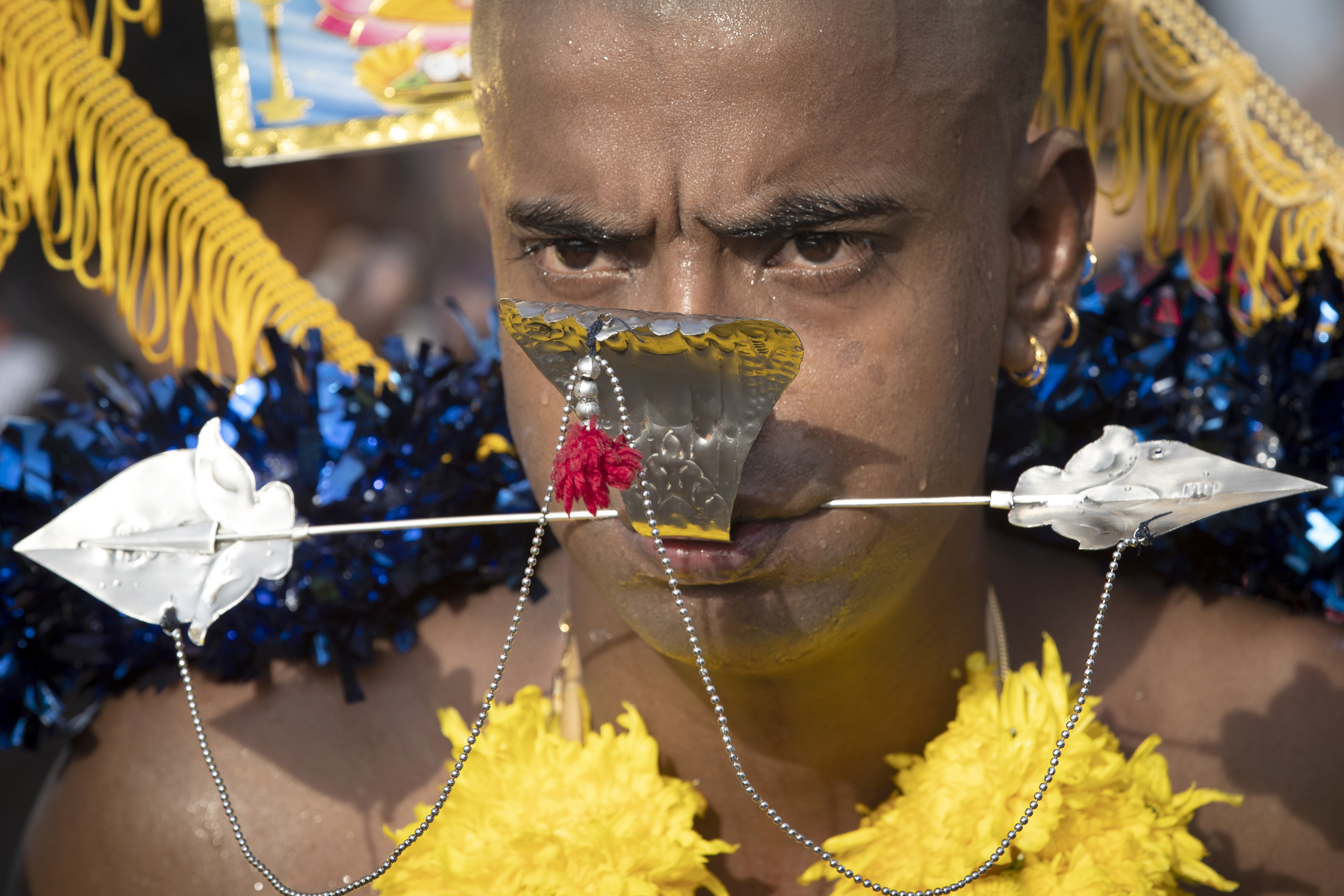 A Hindu devotee carries a Kavadi offering cage with his cheek pierced with a metal rod in a procession during the Thaipusam festival at Batu Caves in Kuala Lumpur, Malaysia, Monday, Jan. 21, 2019. Thaipusam, which is celebrated in honor of Hindu god Lord Murugan, is an annual procession by Hindu devotees seeking blessings, fulfilling vows and offering thanks. (AP Photo/Vincent Thian)
