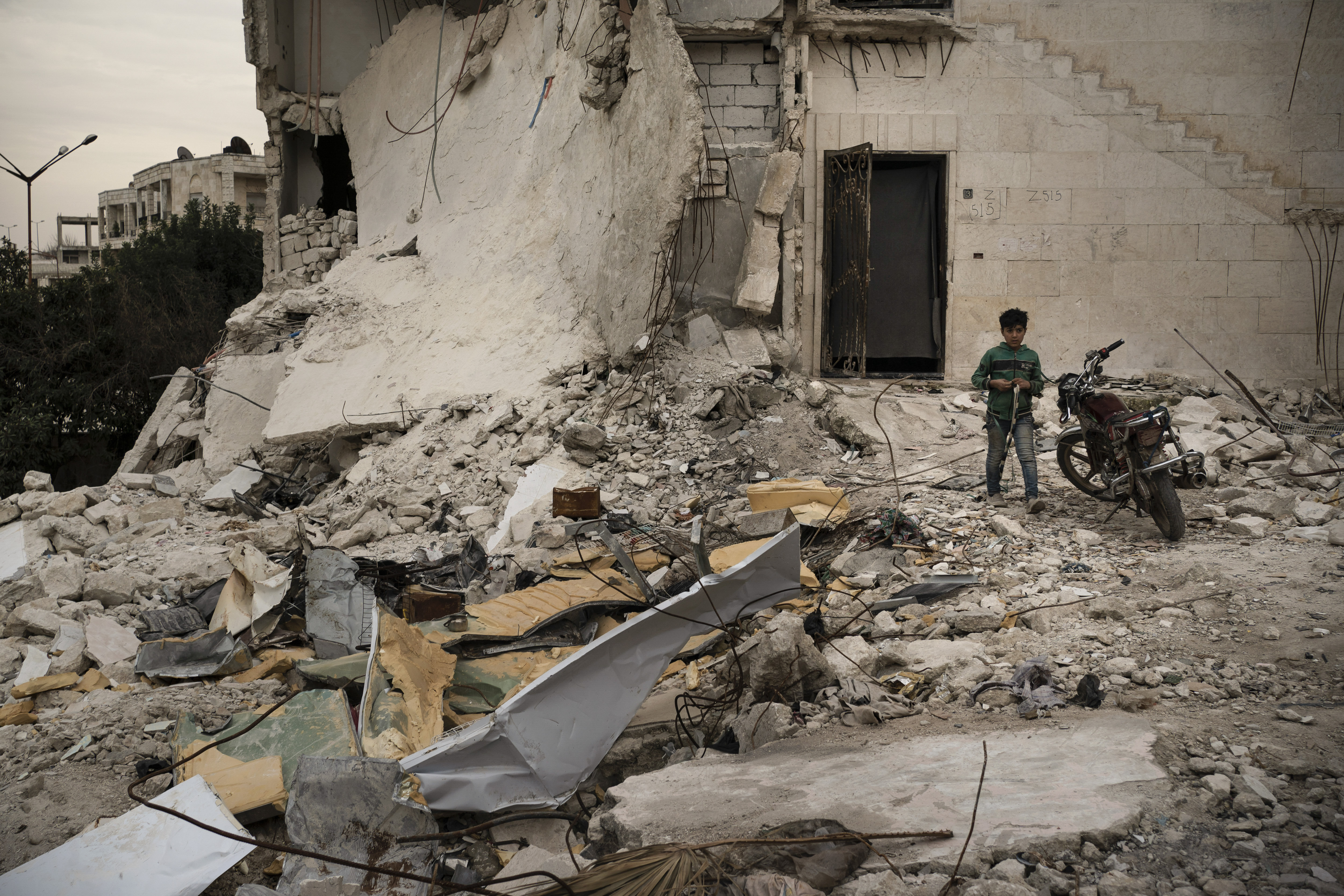 In this Thursday, March 12, 2020 photo, a boy walks out of a heavily damaged building, where he is currently living, in Idlib, Syria. Idlib city is the last urban area still under opposition control in Syria, located in a shrinking rebel enclave in the northwestern province of the same name. Syria’s civil war, which entered its 10th year Monday, March 15, 2020, has shrunk in geographical scope -- focusing on this corner of the country -- but the misery wreaked by the conflict has not diminished. (AP Photo/Felipe Dana)