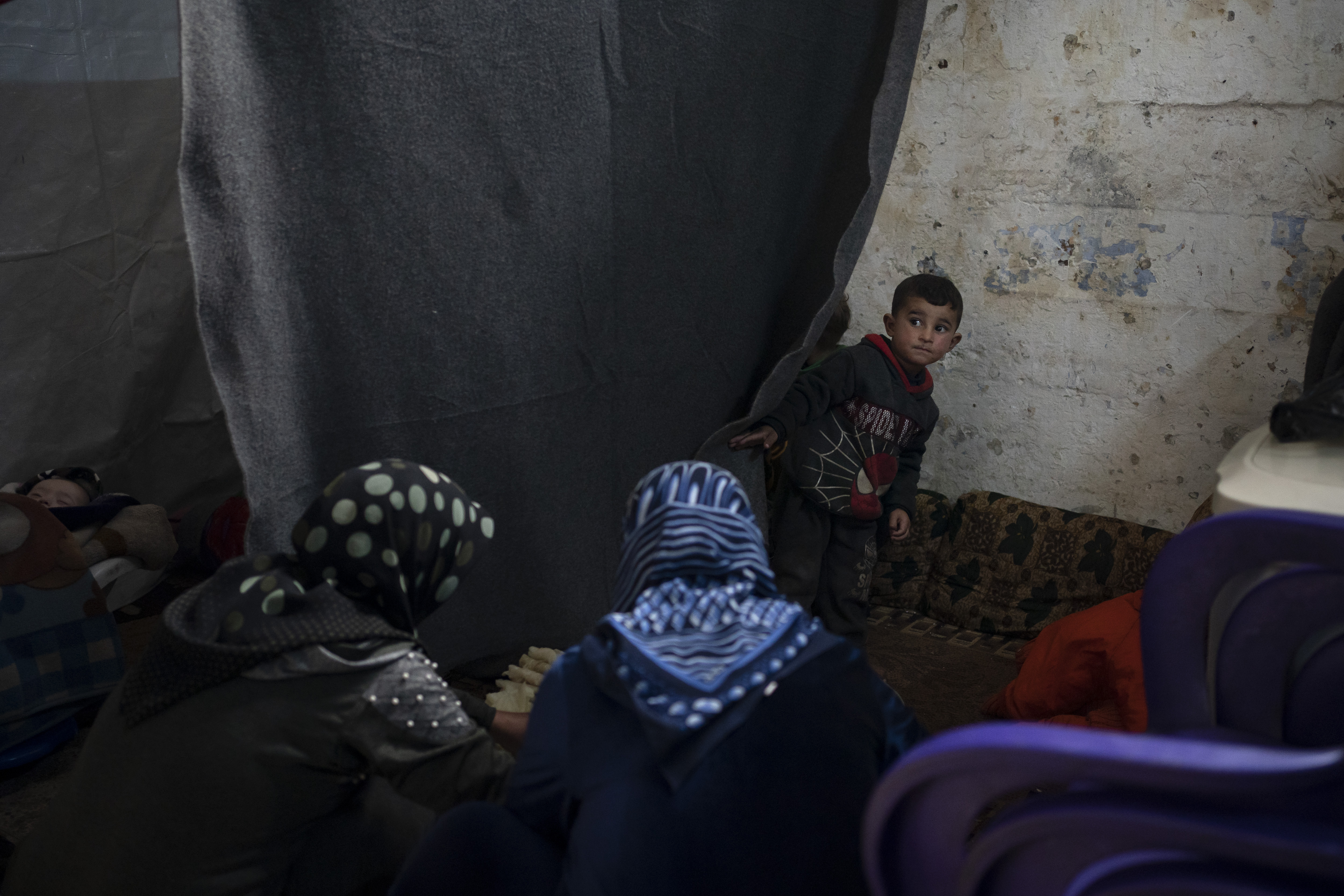 In this Thursday, March 12, 2020 photo, women prepare food in a room inside Idlib's old central prison, now transformed into a camp for people displaced by fighting, in Idlib, Syria. Idlib city is the last urban area still under opposition control in Syria, located in a shrinking rebel enclave in the northwestern province of the same name. Syria’s civil war, which entered its 10th year Monday, March 15, 2020, has shrunk in geographical scope -- focusing on this corner of the country -- but the misery wreaked by the conflict has not diminished. (AP Photo/Felipe Dana)