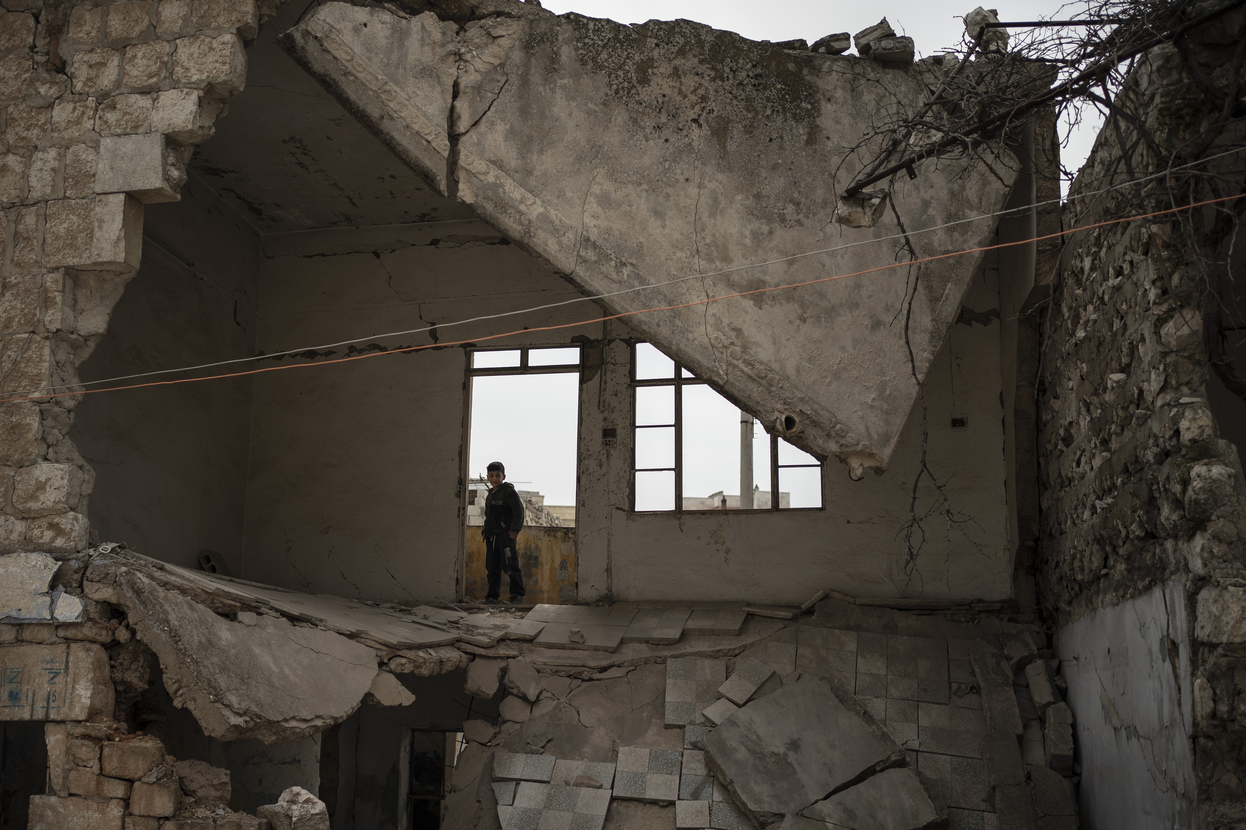 In this Thursday, March 12, 2020 photo, a boy stands inside a house destroyed by an airstrike, in Idlib, Syria. Idlib city is the last urban area still under opposition control in Syria, located in a shrinking rebel enclave in the northwestern province of the same name. Syria’s civil war, which entered its 10th year Monday, March 15, 2020, has shrunk in geographical scope -- focusing on this corner of the country -- but the misery wreaked by the conflict has not diminished. (AP Photo/Felipe Dana)