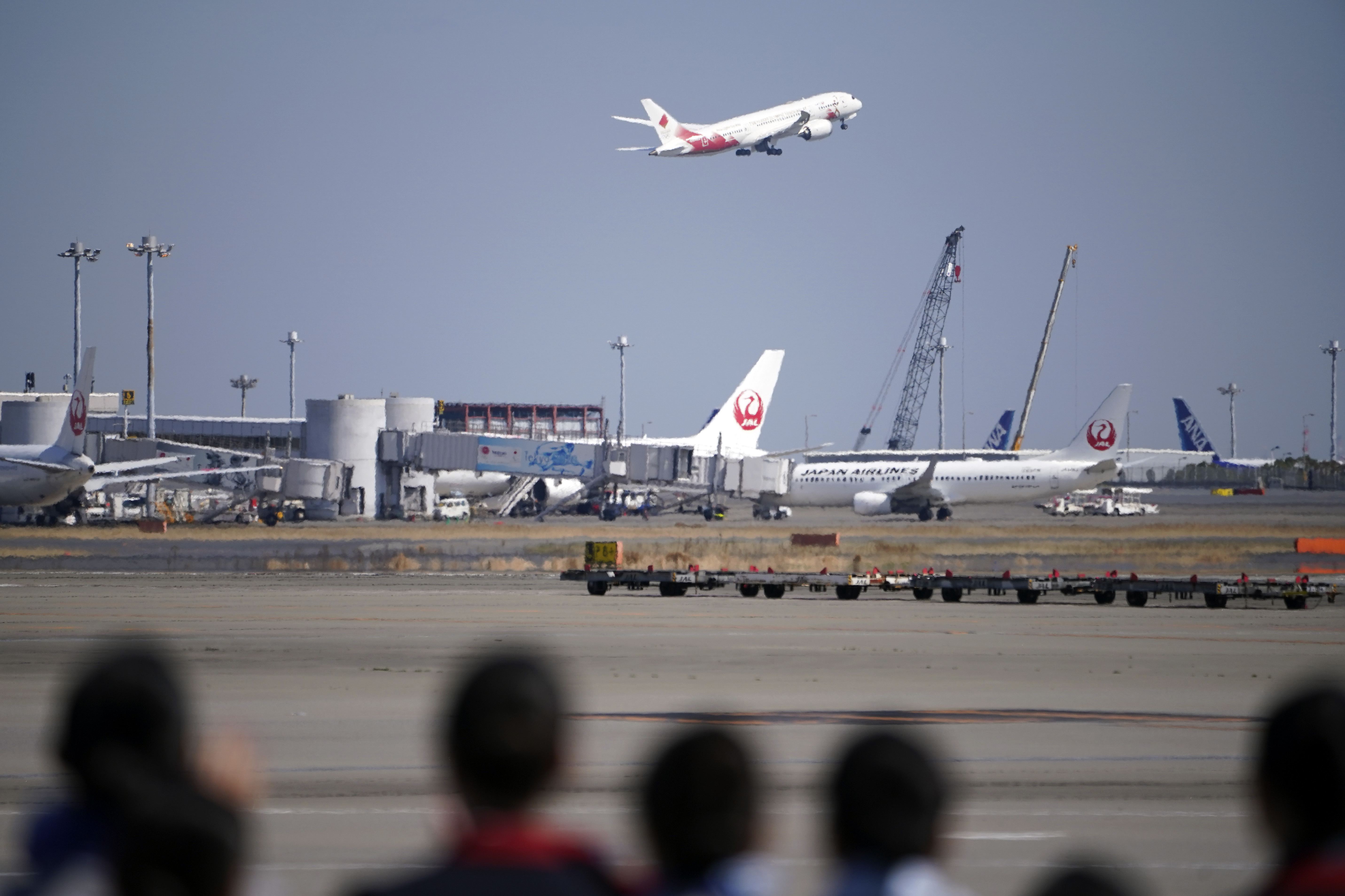 Ground crews of Japanese airlines observe the special "Tokyo 2020 Go" aircraft that will transport the Olympic Flame to Japan from Greece, on its departure at Haneda International Airport in Tokyo Wednesday, March 18, 2020. (AP Photo/Eugene Hoshiko)