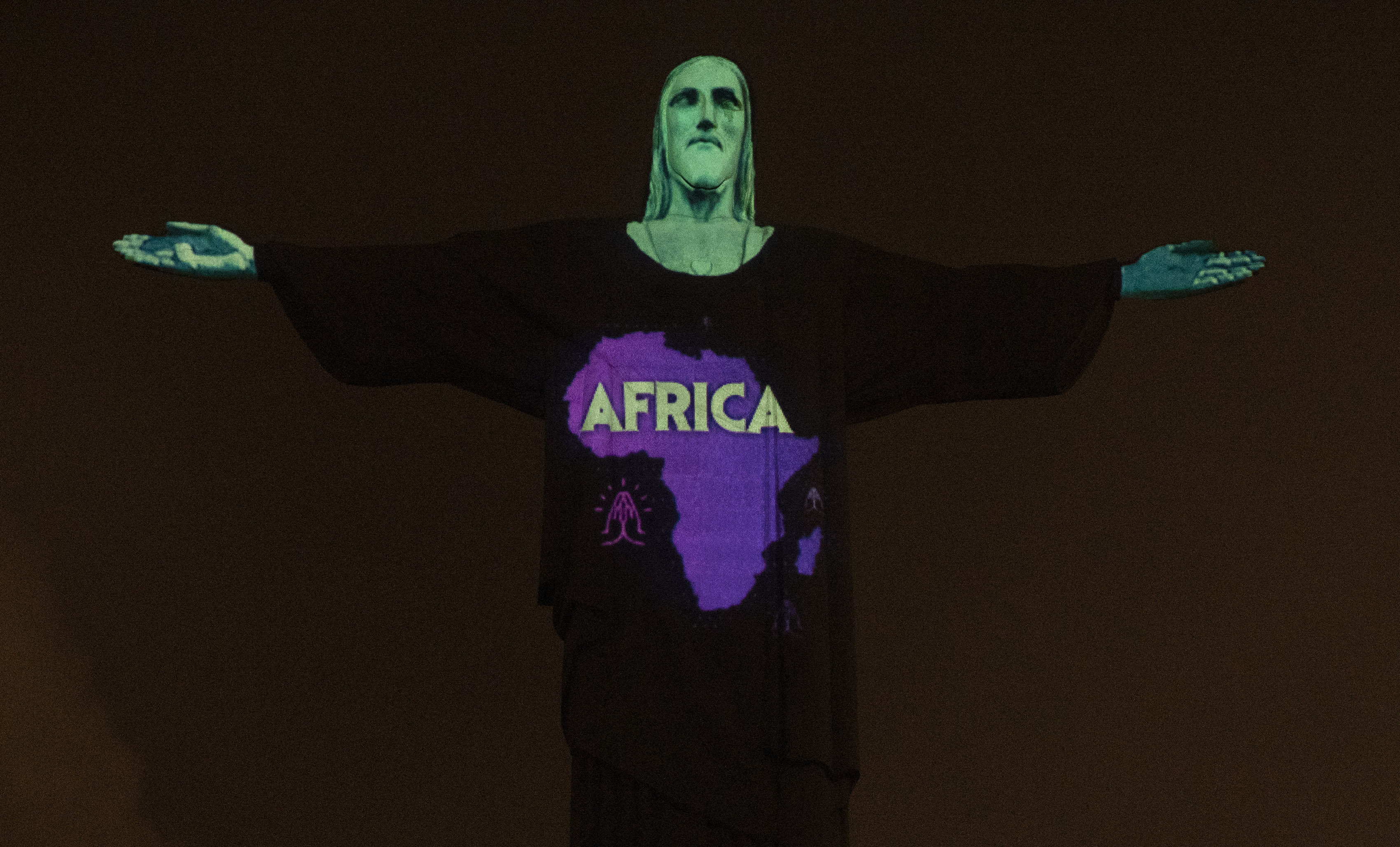Rio's Christ the Redeemer statue is lit up with the map and word Africa, in support of those afflicted by the new coronavirus, in Rio de Janeiro, Brazil, Wednesday, March 18, 2020. For most people COVID-19 causes mild or moderate symptoms. For others, especially the elderly and people with existing health problems, it can cause many other serious illnesses, including pneumonia. (AP Photo/Silvia Izquierdo)