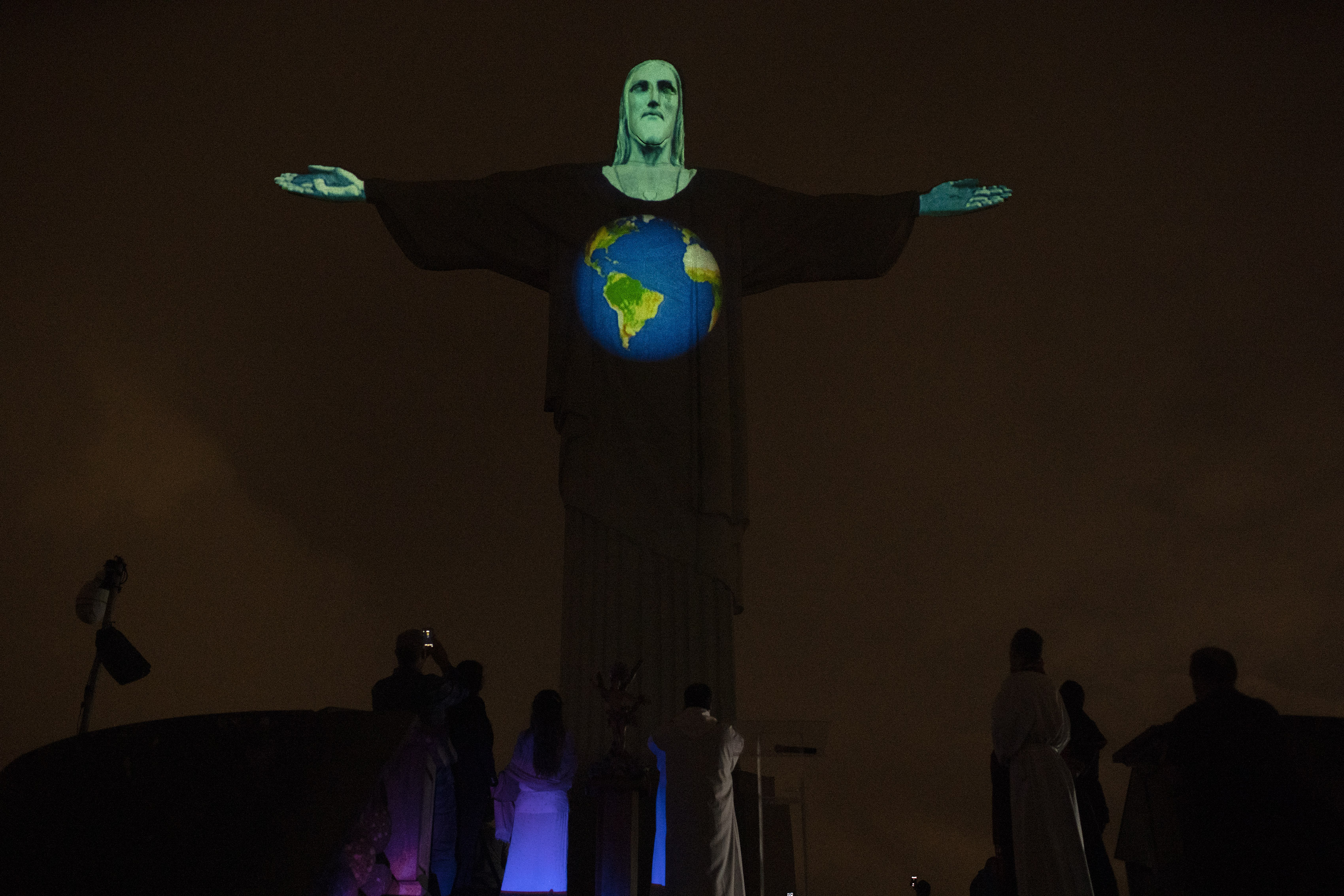 Rio's Christ the Redeemer statue is lit up with an image of the earth, as a way to show support for those afflicted by the new coronavirus, in Rio de Janeiro, Brazil, Wednesday, March 18, 2020. For most people COVID-19 causes mild or moderate symptoms. For others, especially the elderly and people with existing health problems, it can cause many other serious illnesses, including pneumonia. (AP Photo/Silvia Izquierdo)