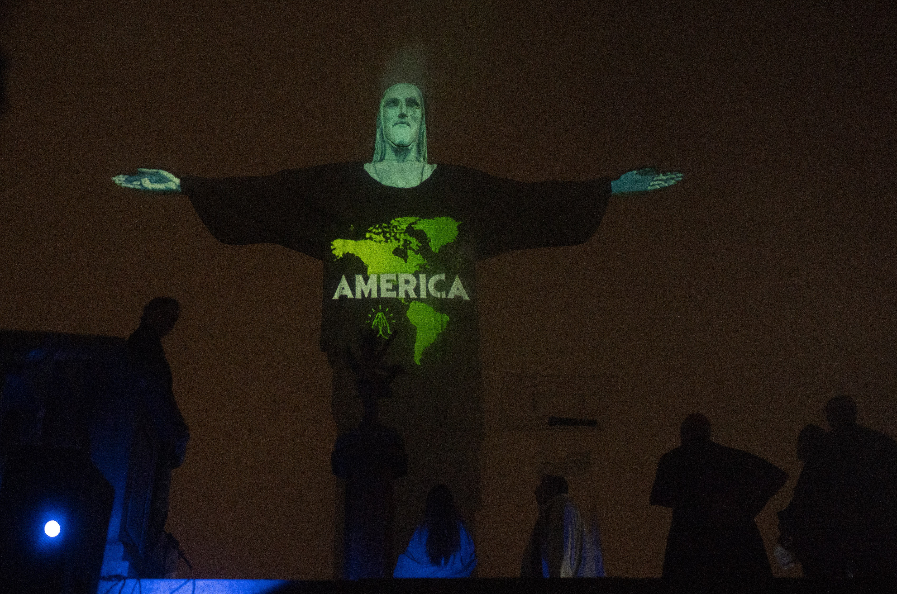 Rio's Christ the Redeemer statue is lit up with a map and the word America, in support of those afflicted by the new coronavirus in Rio de Janeiro, Brazil, Wednesday, March 18, 2020. For most people COVID-19 causes mild or moderate symptoms. For others, especially the elderly and people with existing health problems, it can cause many other serious illnesses, including pneumonia. (AP Photo/Silvia Izquierdo)