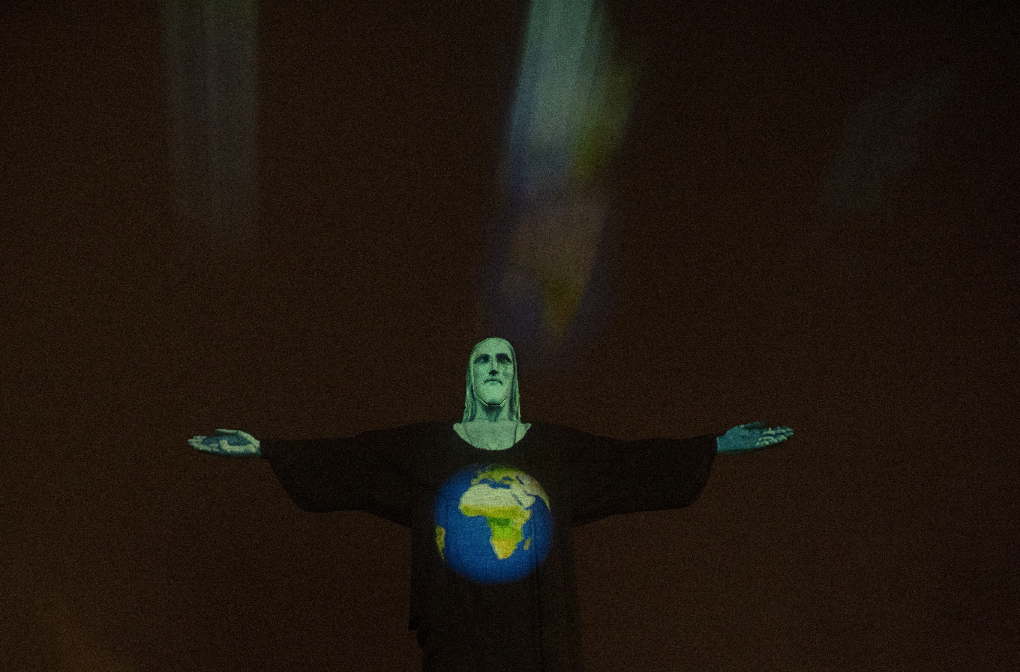 Rio's Christ the Redeemer statue is lit up with an image of the earth, as a way to show support for those afflicted by the new coronavirus, in Rio de Janeiro, Brazil, Wednesday, March 18, 2020. For most people COVID-19 causes mild or moderate symptoms. For others, especially the elderly and people with existing health problems, it can cause many other serious illnesses, including pneumonia. (AP Photo/Silvia Izquierdo)