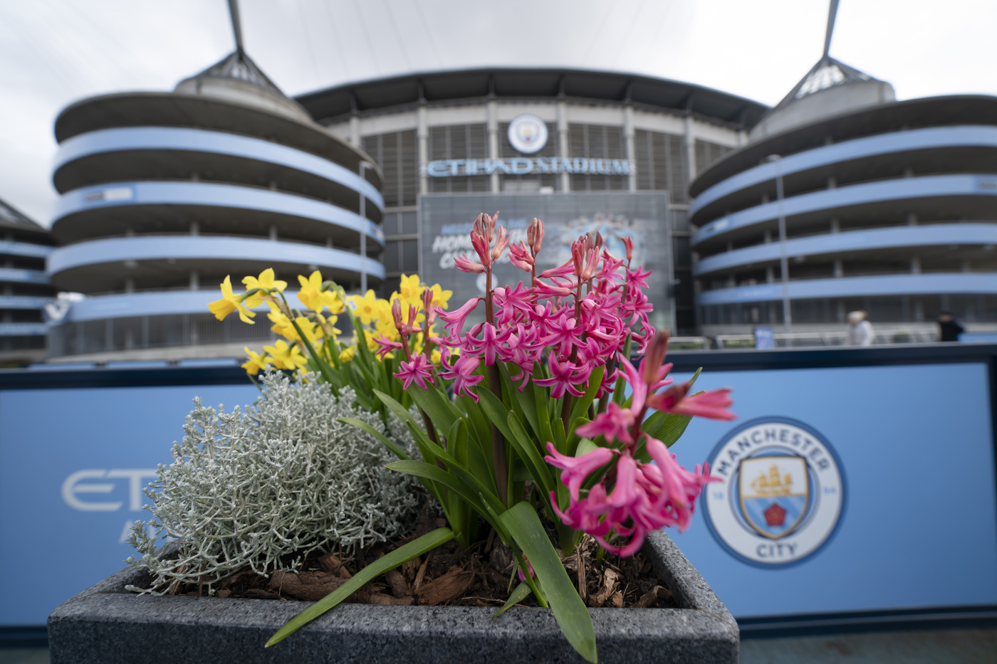 Spring flowers are seen outside the Etihad Stadium where Manchester City was due to play Burnley in an English Premier League soccer match Saturday March 14, 2020, after all English soccer games were cancelled due to the spread of the COVID-19 Coronavirus. For most people, the new COVID-19 coronavirus causes only mild or moderate symptoms, but for some it can cause more severe illness. (AP Photo/Jon Super)
