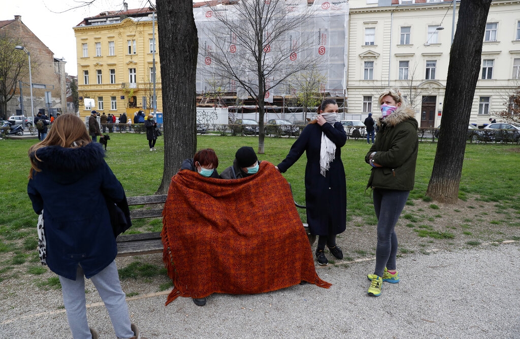 People rest in park after an earthquake in Zagreb, Croatia, Sunday, March 22, 2020. A strong earthquake shook Croatia and its capital on Sunday, causing widespread damage and panic.(AP Photo/Darko Bandic)