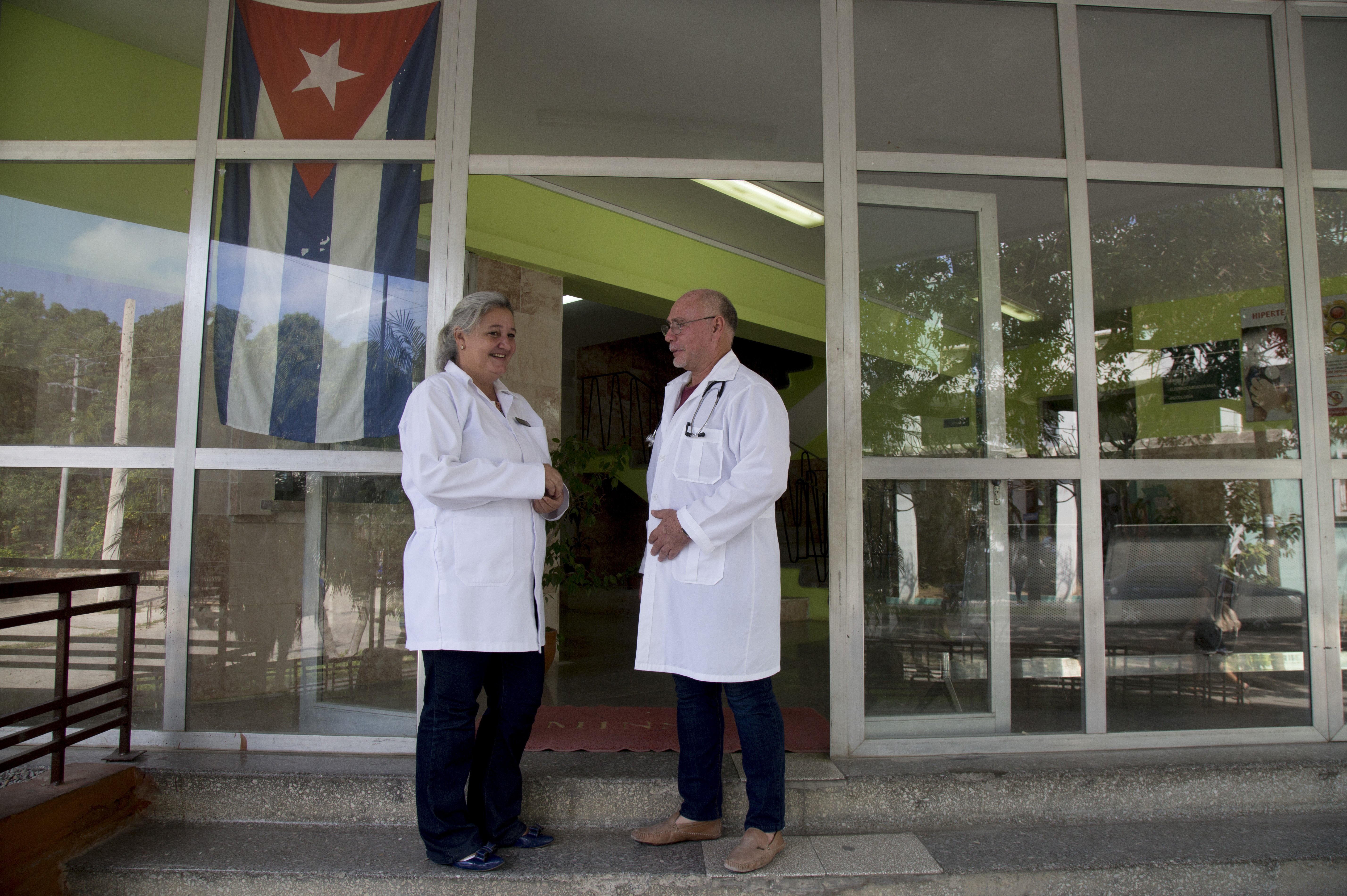 Dr. Zuzel del Valle and Dr. Jorge Cardenas, stand at the entrance of a polyclinic in Havana, Cuba, Wednesday, Feb. 12, 2020.  Hundreds of neighborhood clinics are the front-line defense against contagious diseases in Cuba, providing care to patients seeking relief from colds, aches and minor injuries. (AP Photo/Ismael Francisco)
