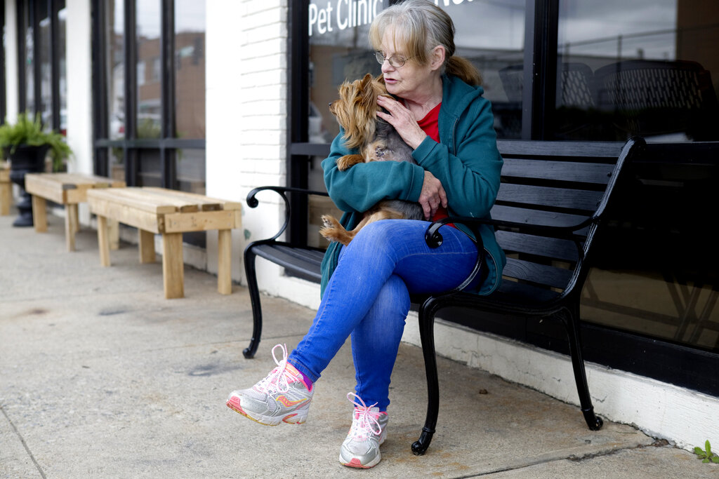 Mary Solomon comforts her dog, Lil Bit while waiting outside of Angels of Assisi to be checked in on Thursday, March 26, 2020, in Roanoke, Va. The low cost vet clinic is offering curb side pick up and drop off for animals to reduce people's exposure to the coronavirus.  (Heather Rousseau/The Roanoke Times via AP)