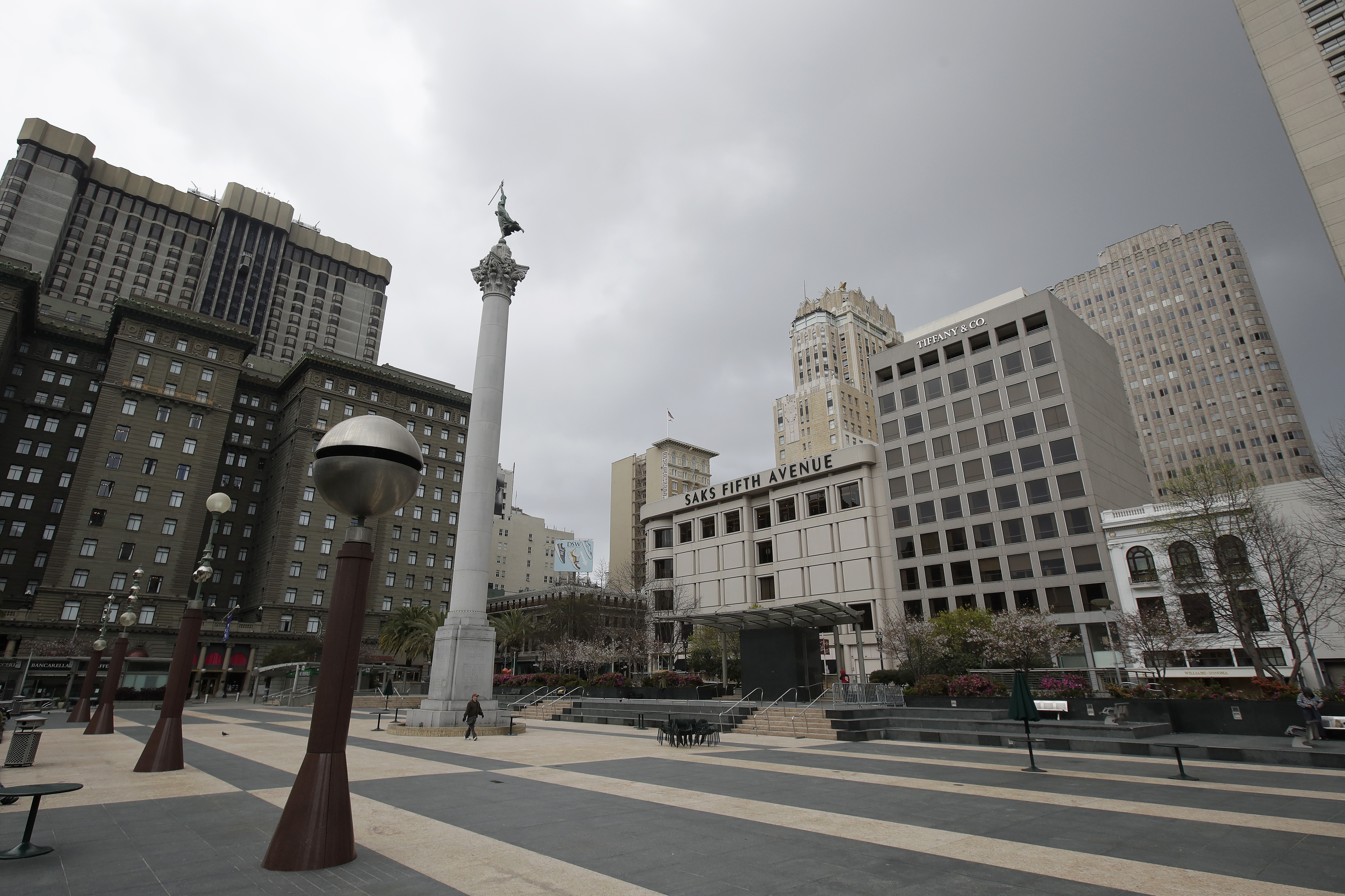 A pedestrian walks through a nearly empty Union Square in San Francisco, Sunday, March 29, 2020. Californians endured a weekend of stepped-up restrictions aimed at keeping them home as much as possible while hospitals and health officials scrambled Sunday to ready themselves for a week that could see the feared dramatic surge in coronavirus cases. (AP Photo/Jeff Chiu)