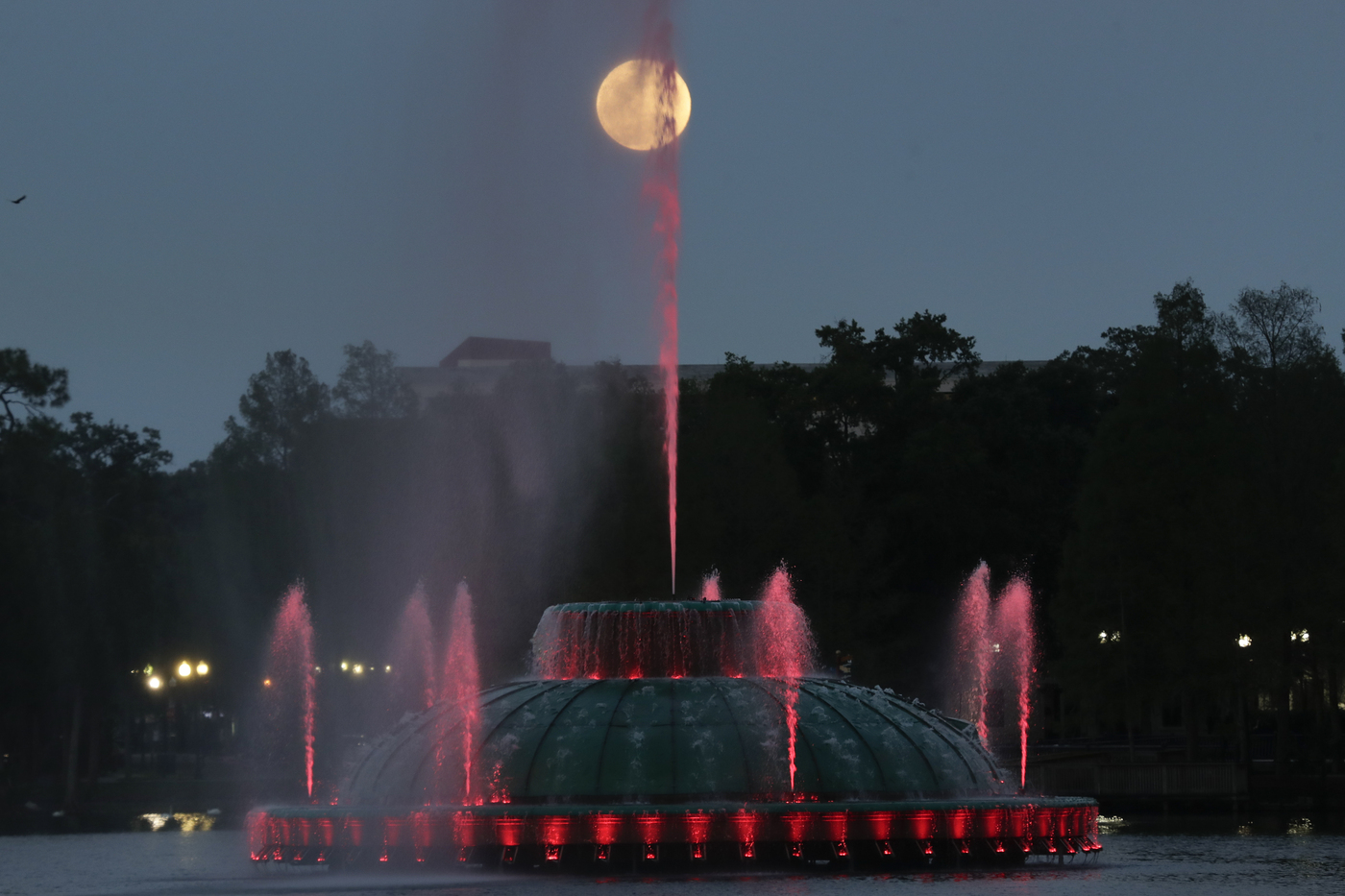 The super moon rises in the sky in front of a fountain a Lake Eola Tuesday, April 7, 2020, in (Orlando, Fla. (AP Photo/John Raoux)