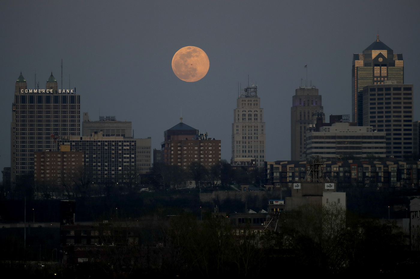 The supermoon rises behind a downtown office building in Kansas City, Mo., Tuesday, April 7, 2020. (AP Photo/Charlie Riedel)