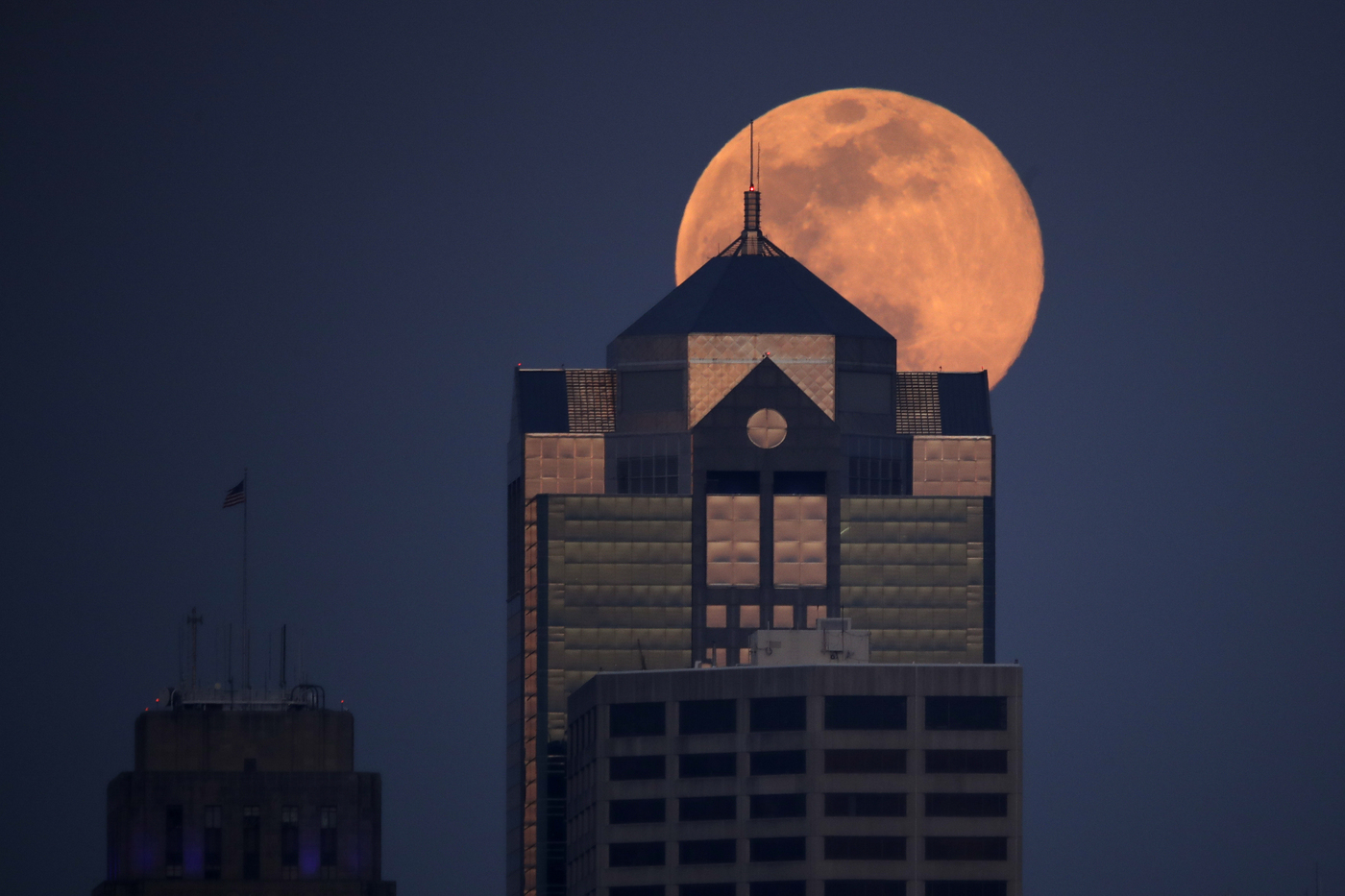 The supermoon rises behind a downtown office building in Kansas City, Mo., Tuesday, April 7, 2020. (AP Photo/Charlie Riedel)