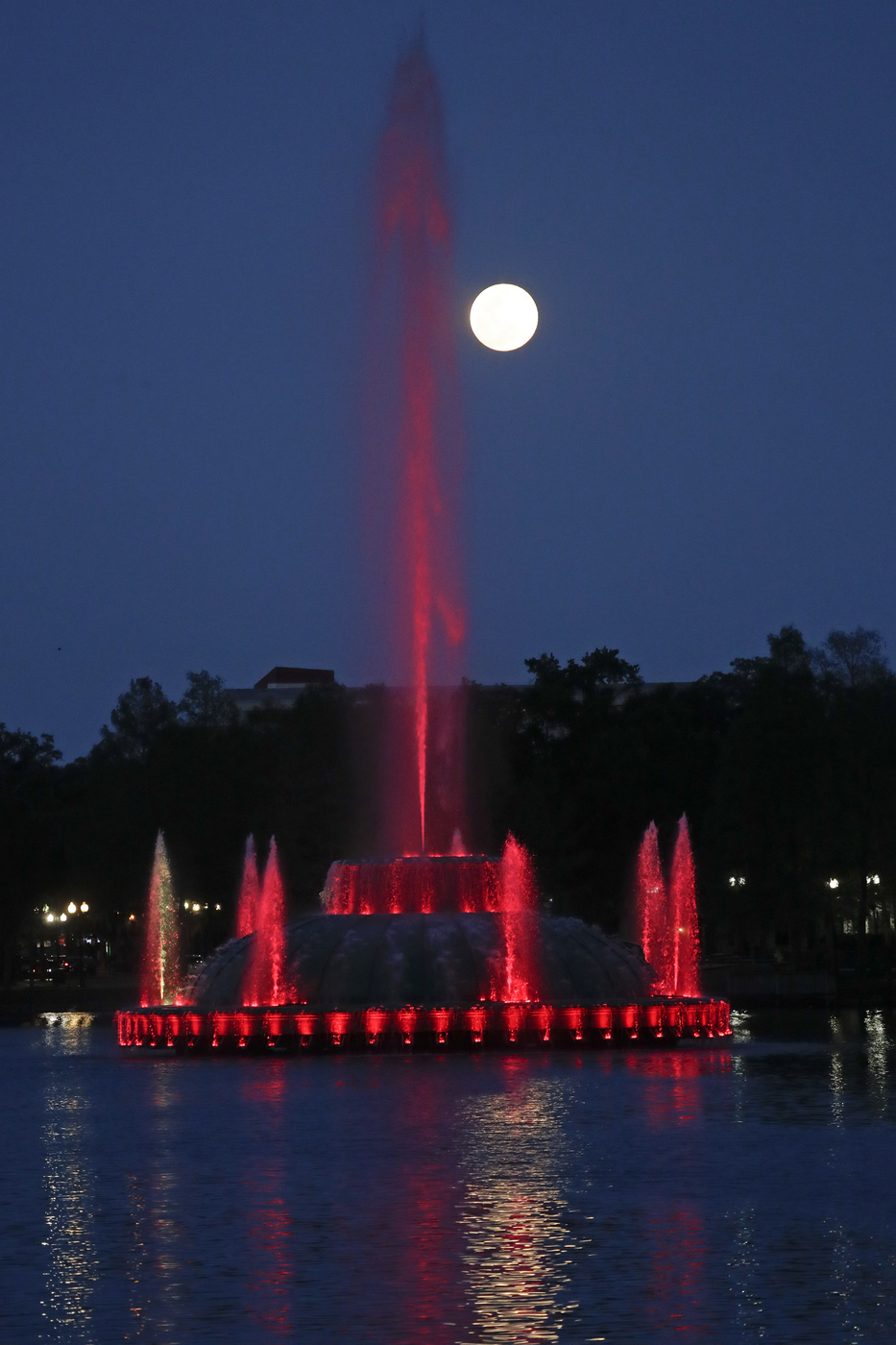 The super moon rises in the sky in front of a fountain a Lake Eola Tuesday, April 7, 2020, in (Orlando, Fla. (AP Photo/John Raoux)