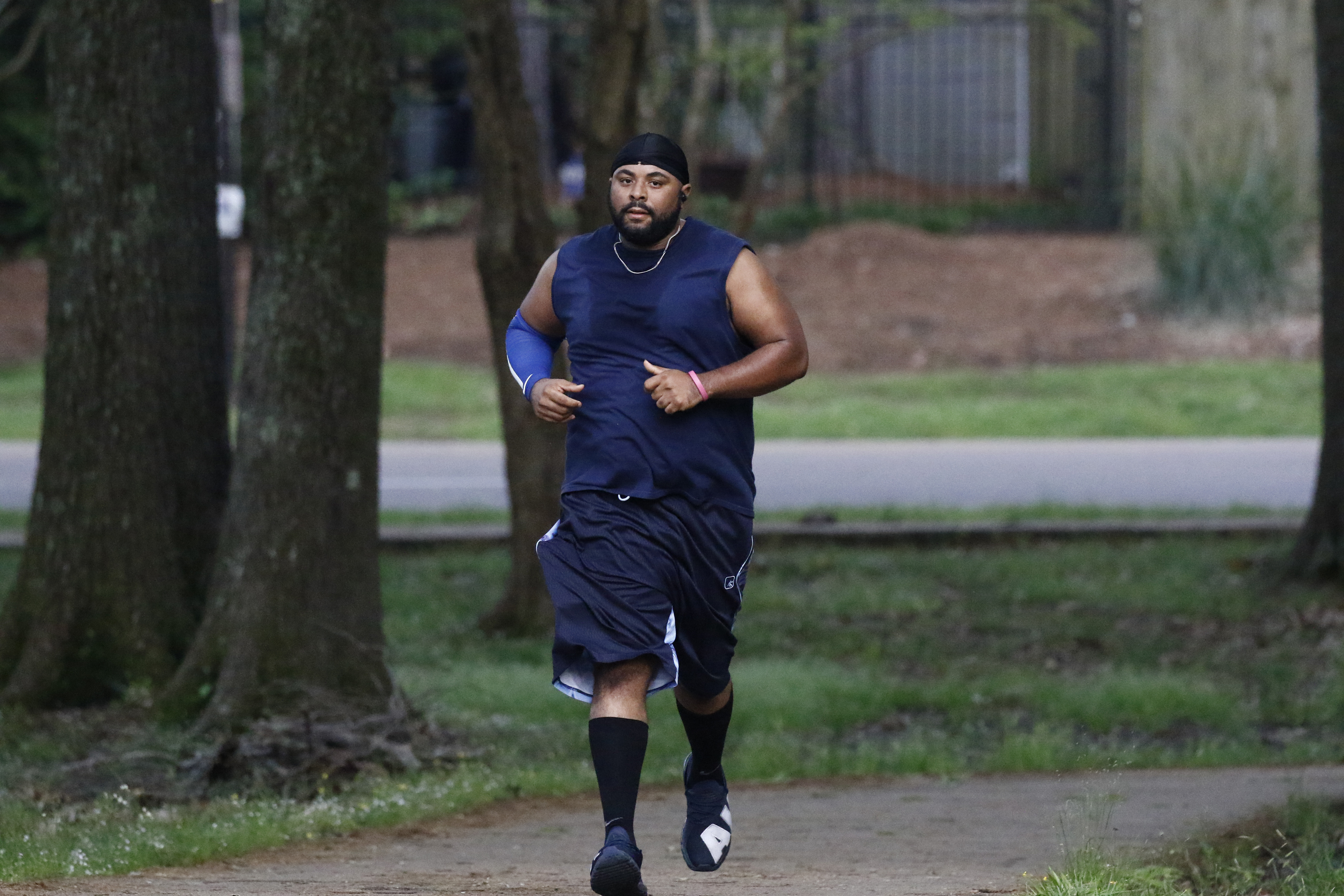 Jelani Houseworth, 41, runs along the 1-mile Parham Bridges walking track, Monday, March 23, 2020, in Jackson, Miss. Runners across the country are still hitting the pavement and the trails, staying fit and working off some stress amid the coronavirus pandemic.  (AP Photo/Rogelio V. Solis)