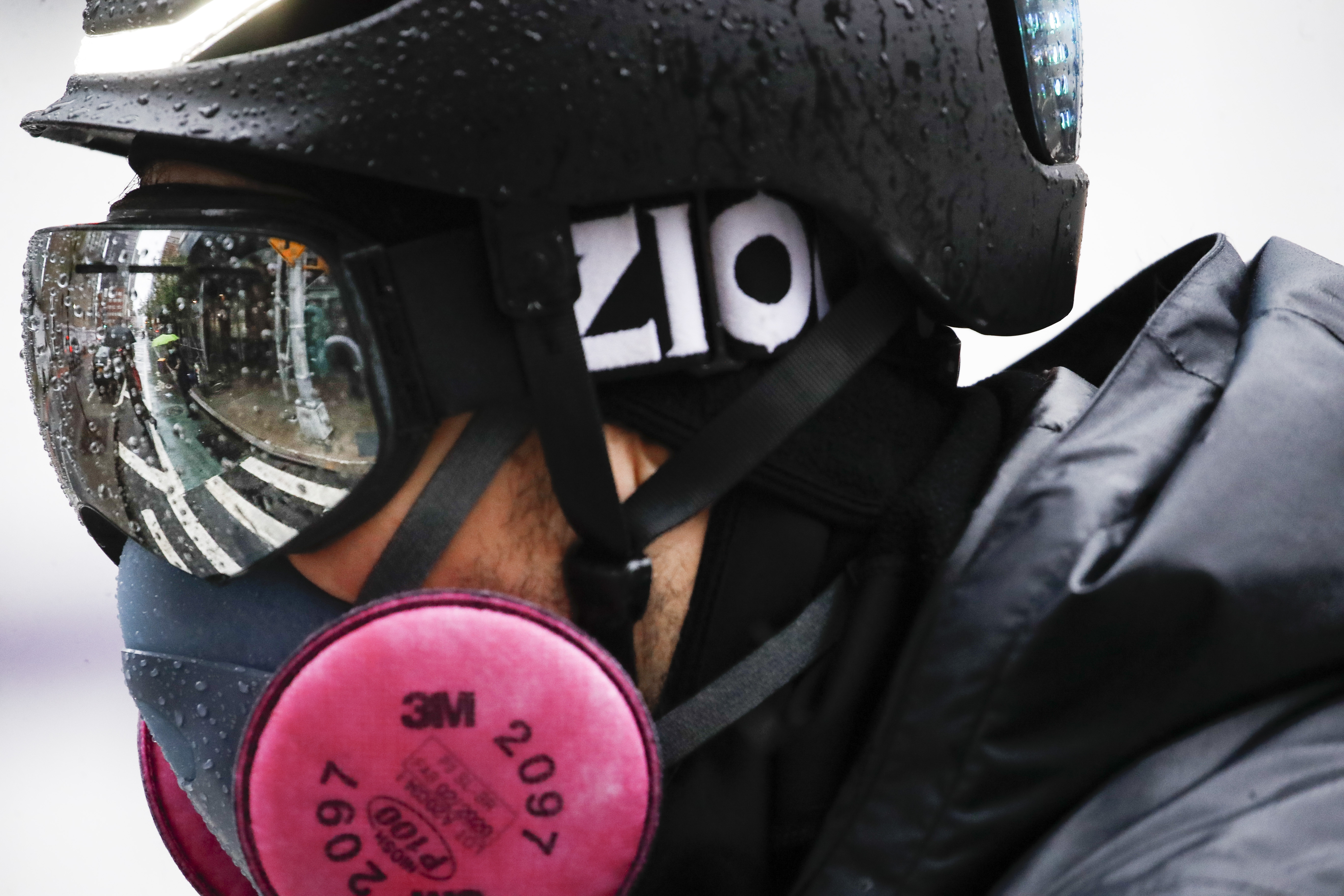 A delivery worker wears personal protective equipment due to COVID-19 concerns while riding a bicycle through the rain outside NYU Langone Medical Center, Monday, April 13, 2020, in New York. The new coronavirus causes mild or moderate symptoms for most people, but for some, especially older adults and people with existing health problems, it can cause more severe illness or death. (AP Photo/John Minchillo)