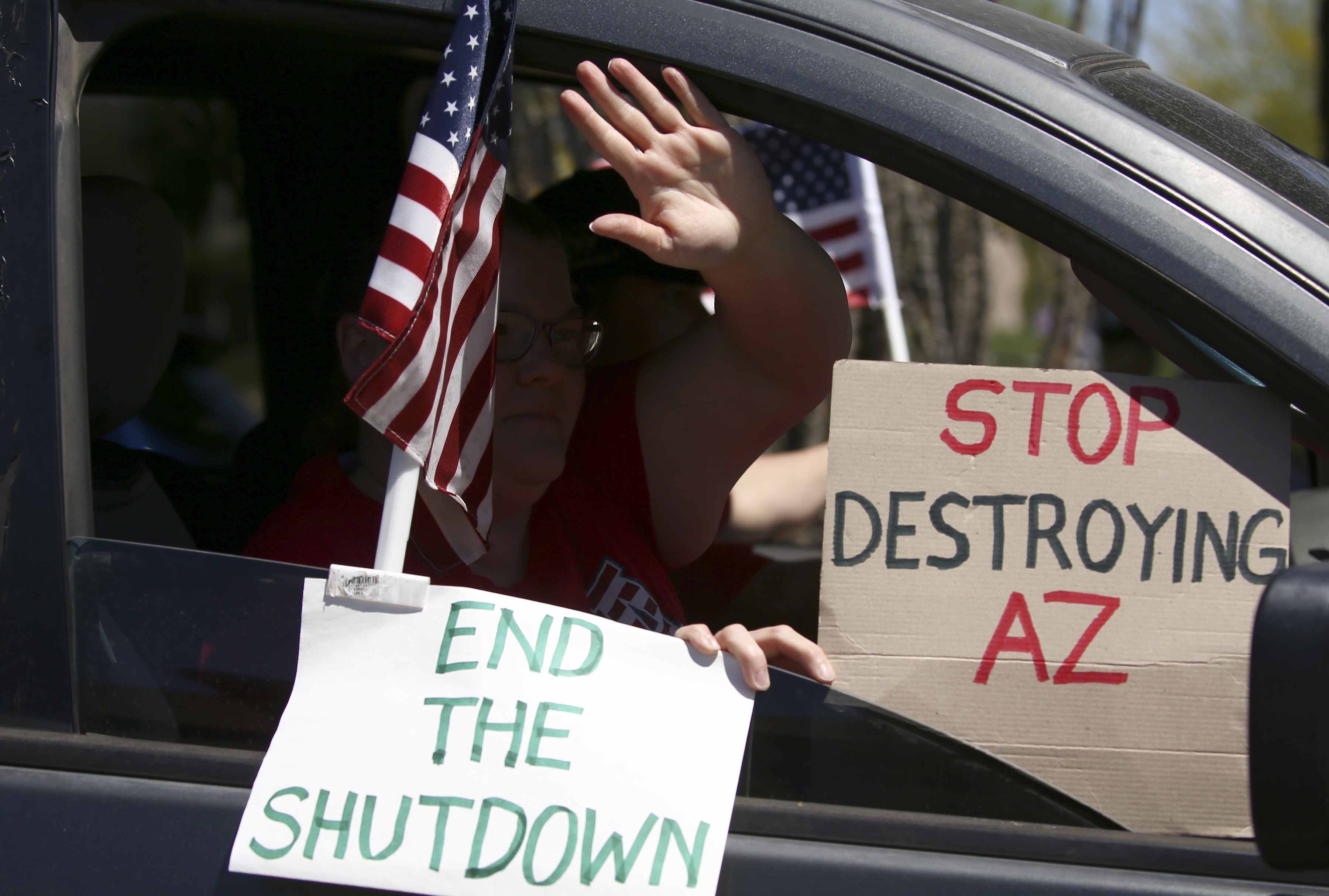 Protesters drive by in support of a rally at the state Capitol to 're-open' Arizona against the governor's stay-at-home order due to the coronavirus Monday, April 20, 2020, in Phoenix. (AP Photo/Ross D. Franklin)