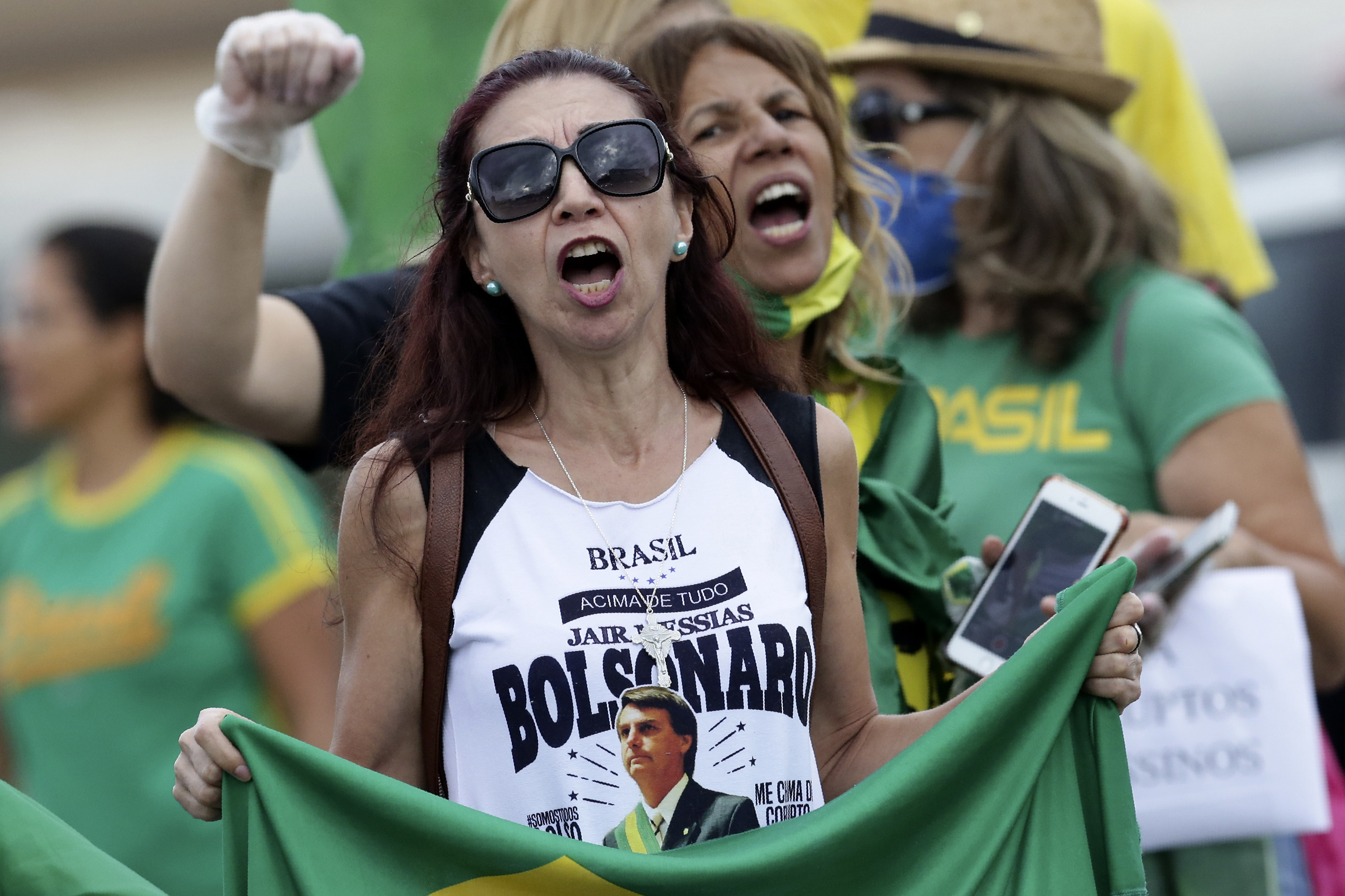 Demonstrators shout slogans against Congreess and the Supreme Court during a protest demanding military intervention during the new coronavirus emergency, in front of the National Congress, in Brasilia, Brazil, Monday, April 20, 2020. (AP Photo/Eraldo Peres)
