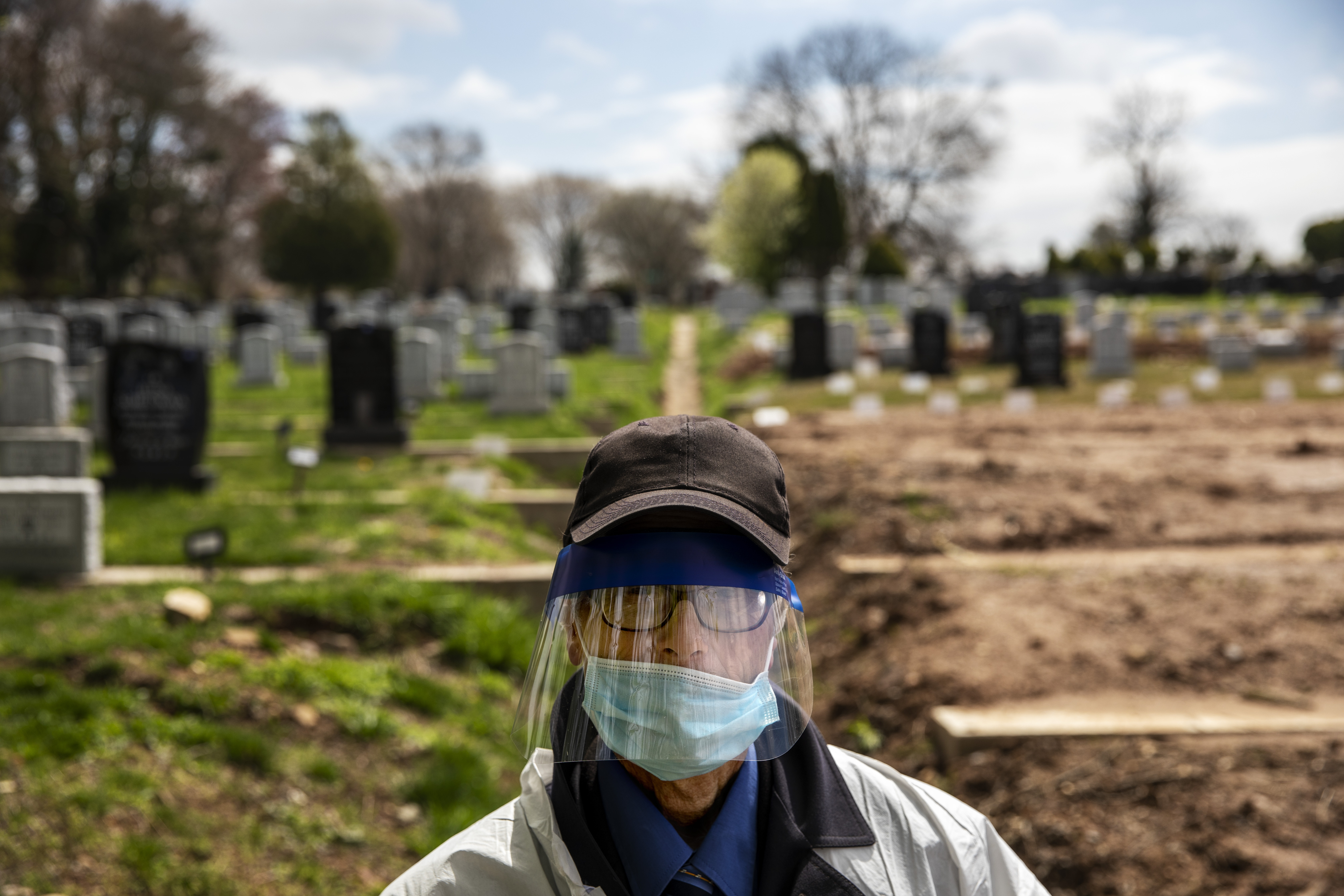 Rabbi Shmuel Plafker walks through Mount Richmond Cemetery after conducting burials of mostly coronavirus victims in the Staten Island borough of New York, Wednesday, April 8, 2020. As the world retreats and the pandemic's confirmed death toll in New York City alone charges past 10,000, funeral directors, cemetery workers and others who oversee a body's final chapter are sprinting to keep up. (AP Photo/David Goldman)
