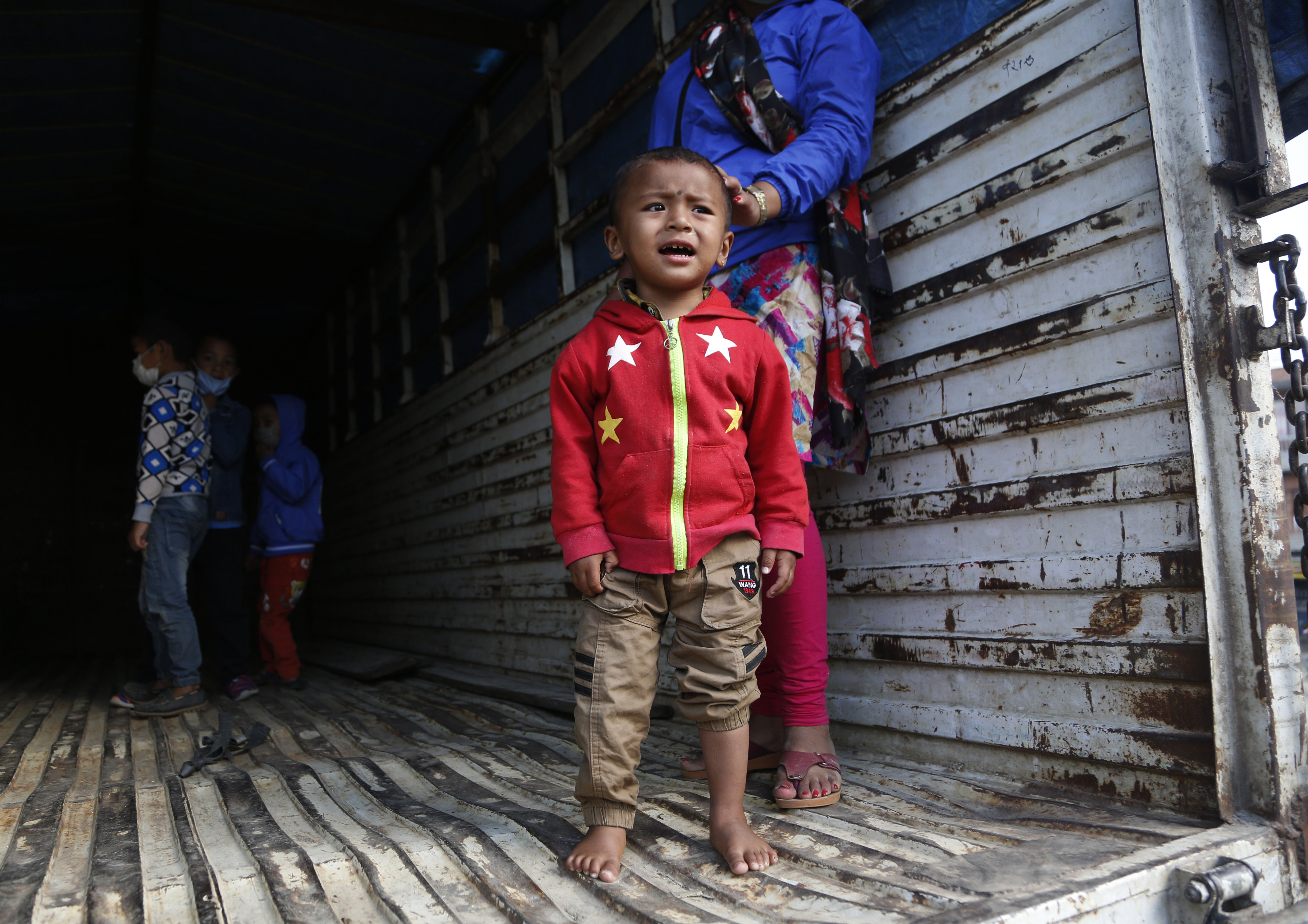A young Nepalese boy cries as he waits for his father on a vehicle to go back to their village, during lockdown to prevent the spread of the new coronavirus in Bhaktapur, Nepal, Monday, April 20, 2020. The supreme court passed an interim order on Friday instructing the Nepalese government to ensure free transportation for stranded daily wage workers and others making the long journey back to their respective villages on foot. (AP Photo/Niranjan Shrestha)