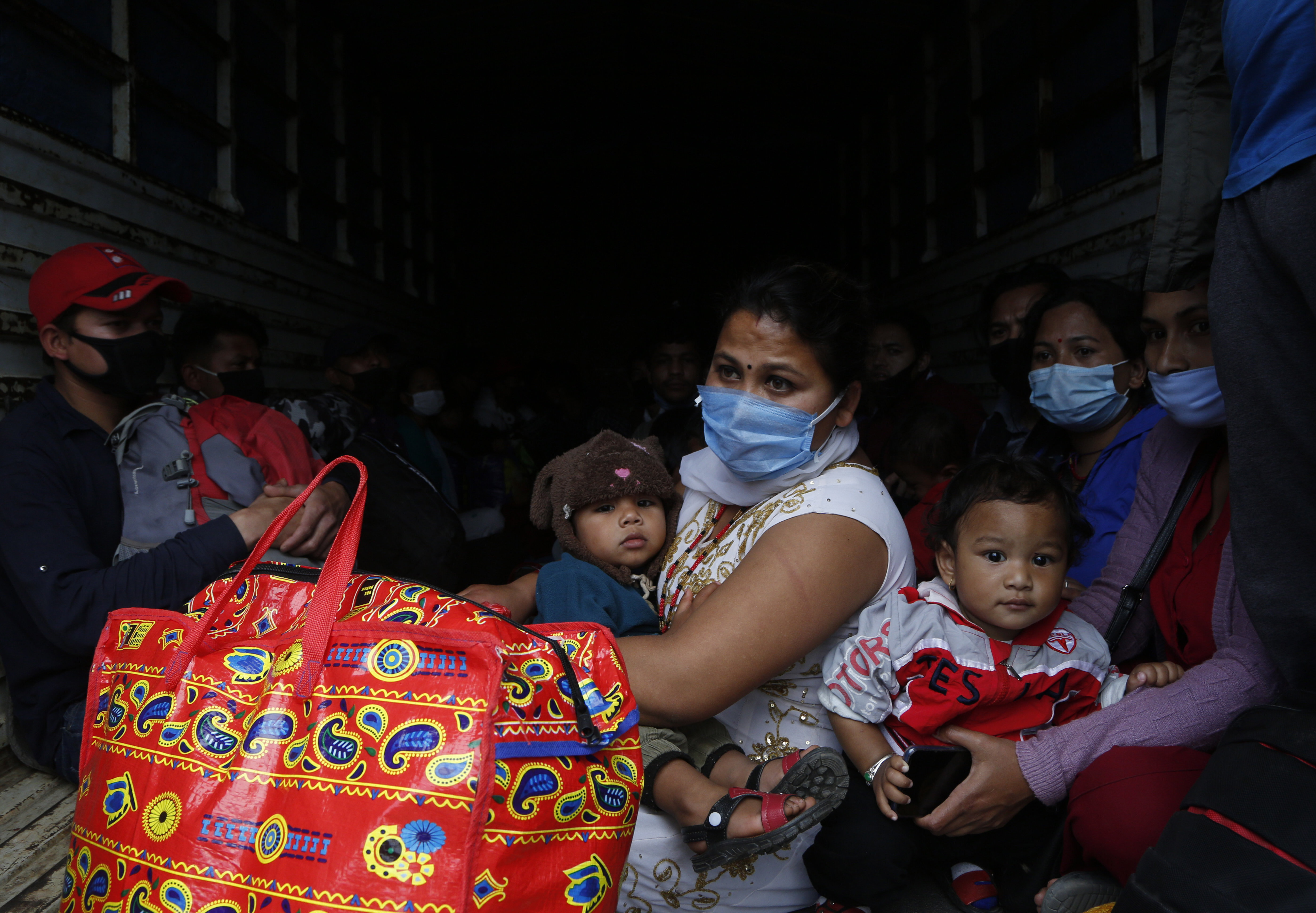 Stranded Nepalese people get ready to travel back to their village on the back of a truck, during lockdown to prevent the spread of the new coronavirus in Bhaktapur, Nepal, Monday, April 20, 2020. The supreme court passed an interim order on Friday instructing the Nepalese government to ensure free transportation for stranded daily wage workers and others making the long journey back to their respective villages on foot. (AP Photo/Niranjan Shrestha)