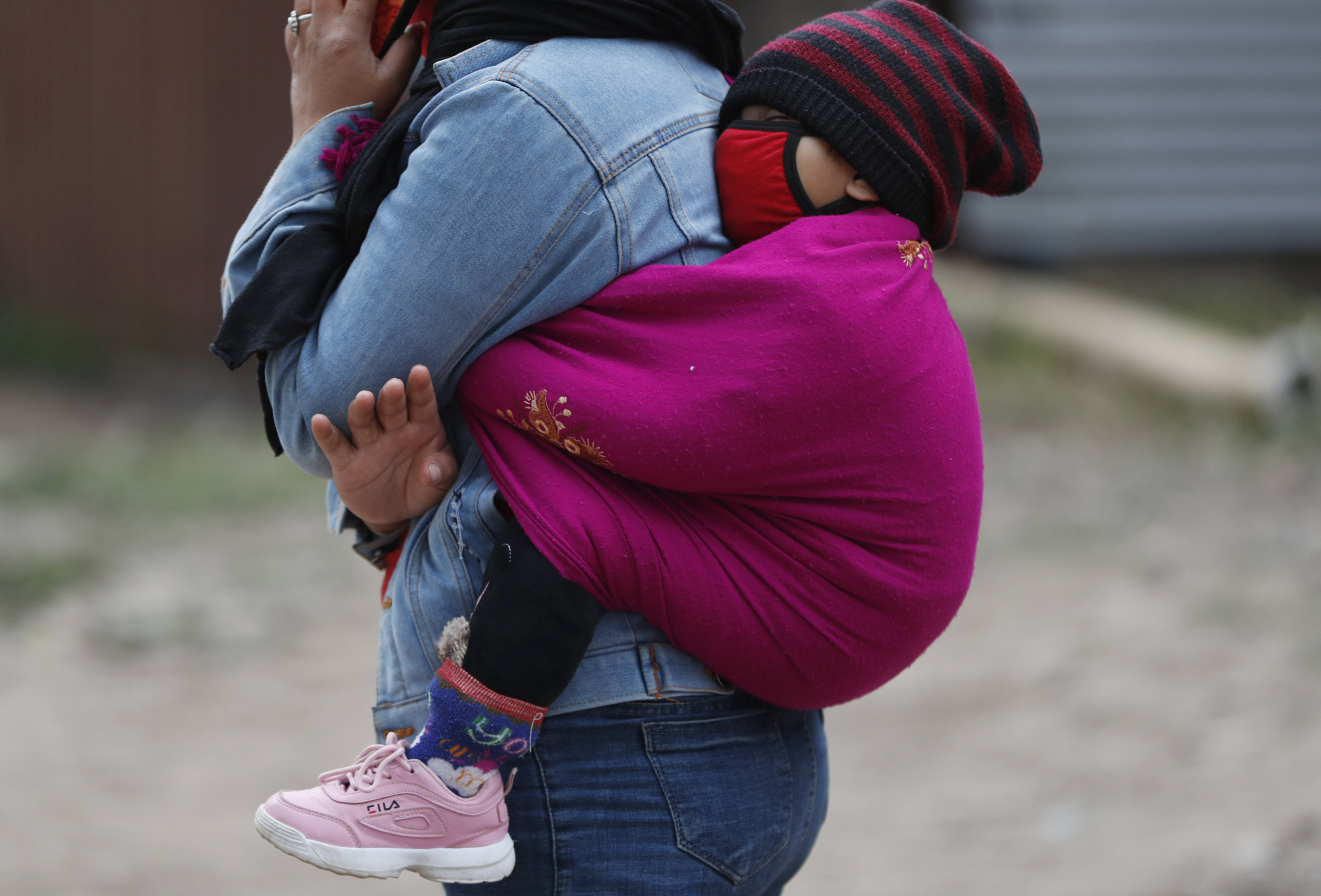 A Nepalese woman carries her child as she waits for a vehicle to go back to her village, during lockdown to prevent the spread of the new coronavirus in Bhaktapur, Nepal, Monday, April 20, 2020. The supreme court passed an interim order on Friday instructing the Nepalese government to ensure free transportation for stranded daily wage workers and others making the long journey back to their respective villages on foot. (AP Photo/Niranjan Shrestha)