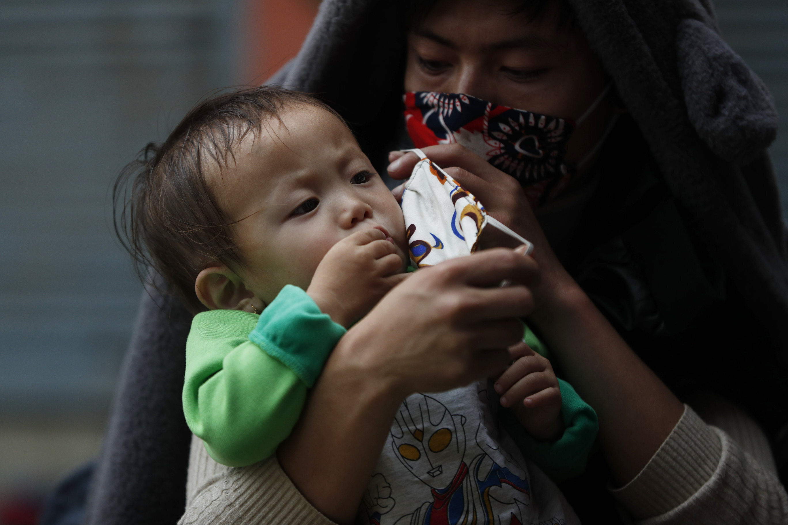 A Nepalese man puts a mask on his child's face as they wait for a vehicle to go back to their village, during lockdown to prevent the spread of the new coronavirus in Bhaktapur, Nepal, Monday, April 20, 2020. The supreme court passed an interim order on Friday instructing the Nepalese government to ensure free transportation for stranded daily wage workers and others making the long journey back to their respective villages on foot. (AP Photo/Niranjan Shrestha)
