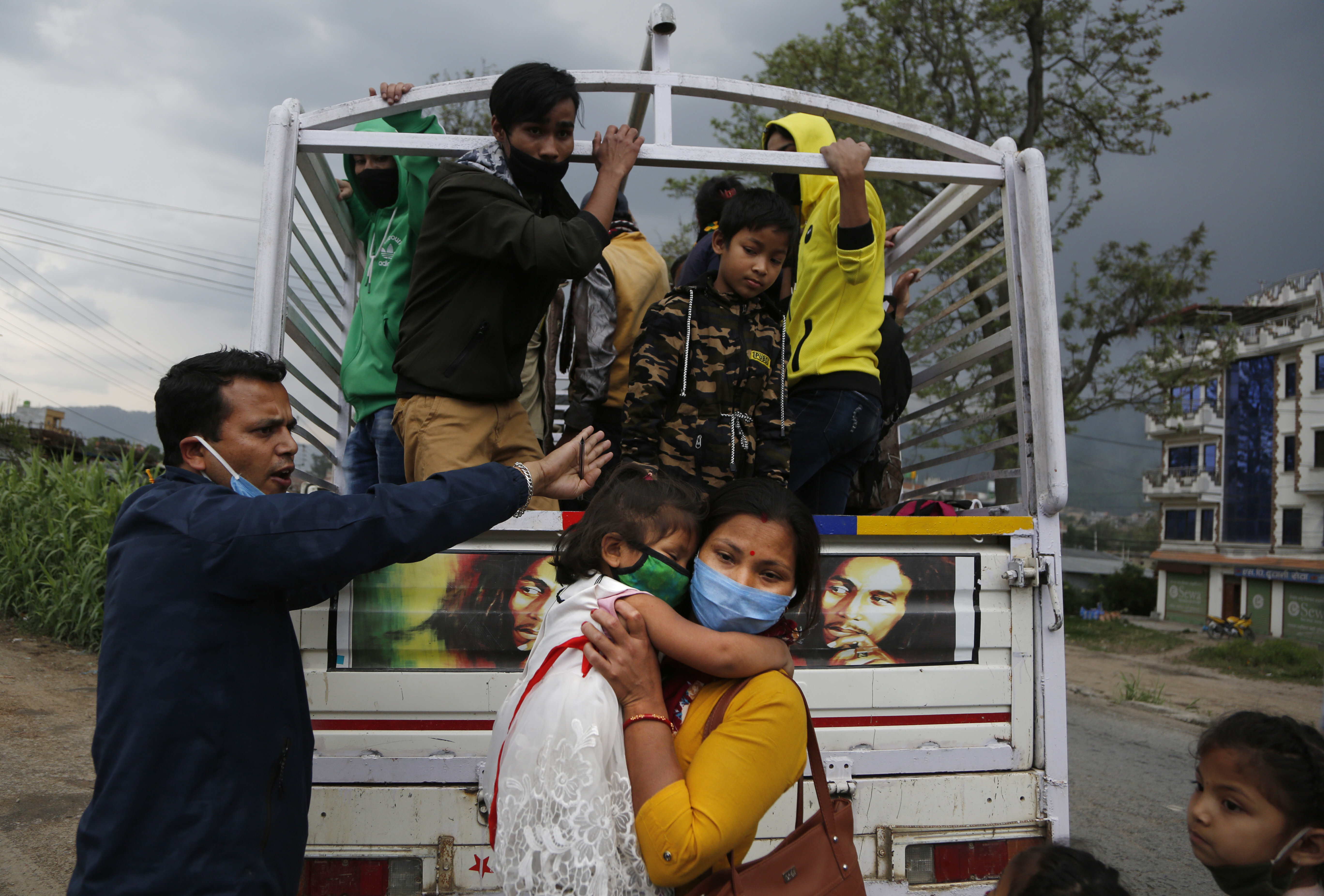 A Nepalese woman carries her child as a volunteer tries to arrange space for them on a vehicle to go back to their village, during lockdown to prevent the spread of the new coronavirus in Bhaktapur, Nepal, Monday, April 20, 2020. The supreme court passed an interim order on Friday instructing the Nepalese government to ensure free transportation for stranded daily wage workers and others making the long journey back to their respective villages on foot. (AP Photo/Niranjan Shrestha)