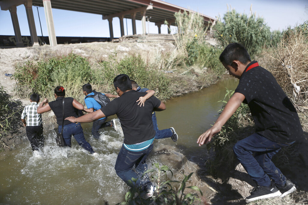 Migrants scramble across the Rio Bravo to surrender to the American authorities, on the US - Mexico border between Ciudad Juarez and El Paso, Saturday, June 15, 2019. (AP Photo/ Photo/Christian Torres)