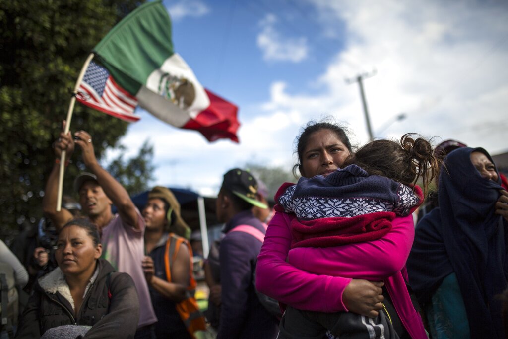 FILE - In this Nov. 22, 2018 file photo, Honduran migrant Leticia Nunes holds her daughter Mailyn amid a small group of migrants trying to make their way to the U.S. as Mexican police in riot gear block them from the Chaparral border crossing in Tijuana, Mexico. U.S. ambassadors from El Salvador, Honduras and Haiti sent urgent cables, made public Thursday, Nov. 7, 2019, to the White House in the early days of the Trump administration, pleading with them to abandon plans to send hundreds of thousands of migrants back to their home countries. (AP Photo/Rodrigo Abd, File)