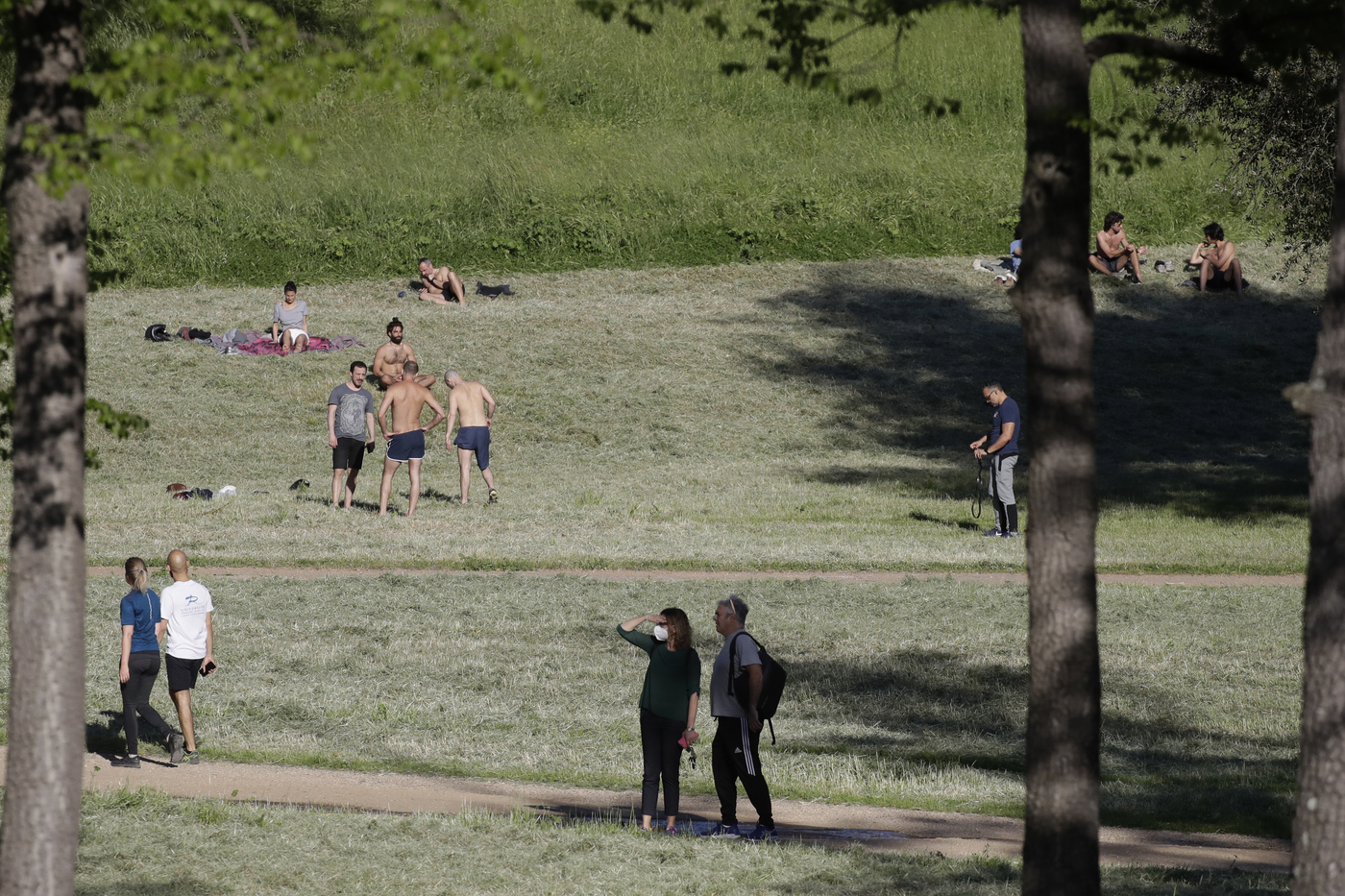 People sunbathe and stroll inside Rome's Villa Pamphili park as it reopened after several weeks of closure, part of nationwide limited easing of some lockdown restrictions, on Monday, May 4, 2020. Italy began stirring again Monday after a two-month coronavirus shutdown, with 4.4 million Italians able to return to work and restrictions on movement eased in the first European country to lock down in a bid to stem COVID-19 infections.  (AP Photo/Alessandra Tarantino)