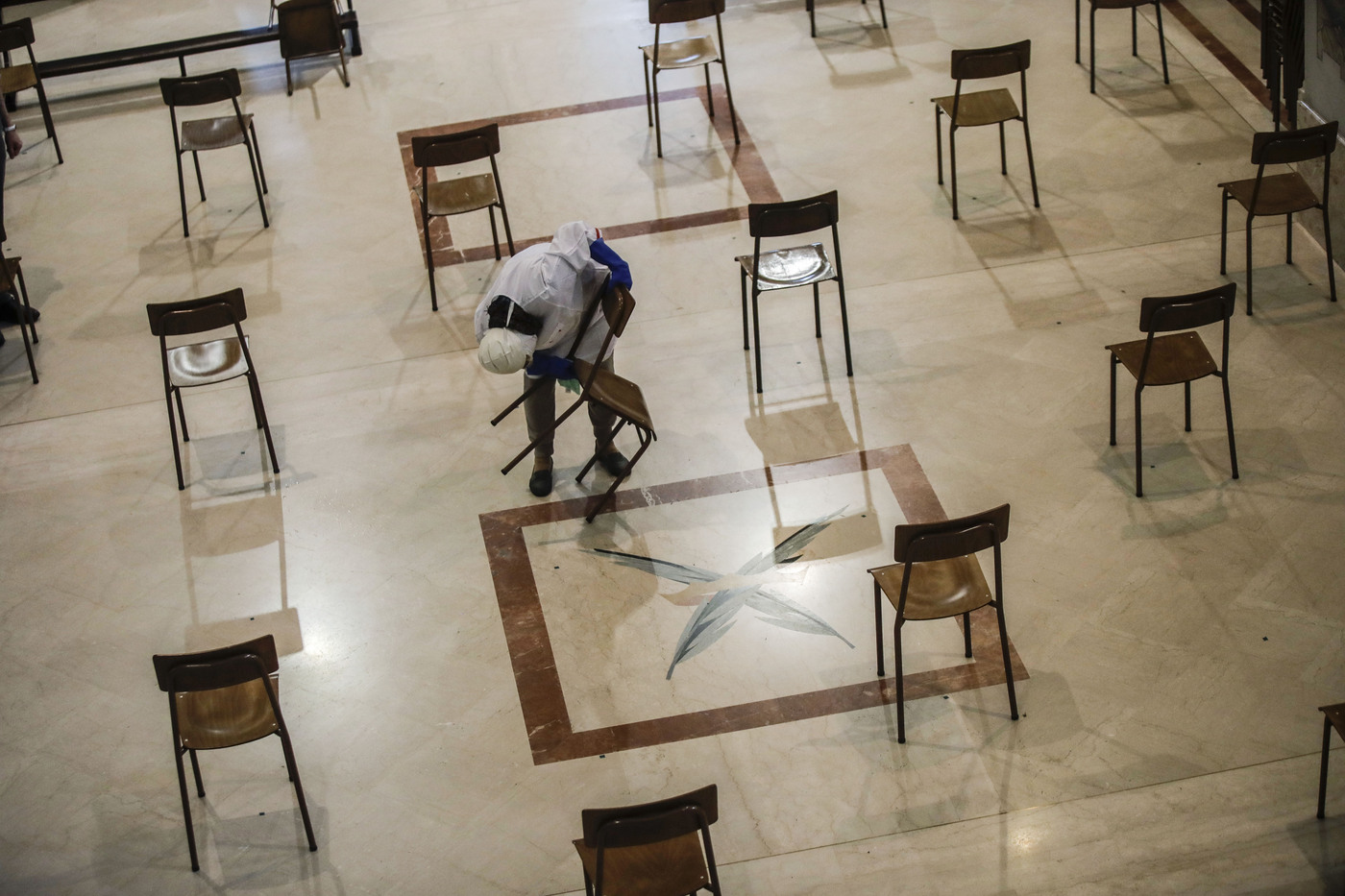 A woman cleans SS. Quirico and Giulitta Church in Giussano, northern Italy, Friday, May 15, 2020, also placing chairs at the correct distance. Churches in Italy are preparing to reopen to the public for masses from May 18 after Italy partially lifted restrictions last week following a two-month lockdown due to COVID-19. (AP Photo/Luca Bruno)